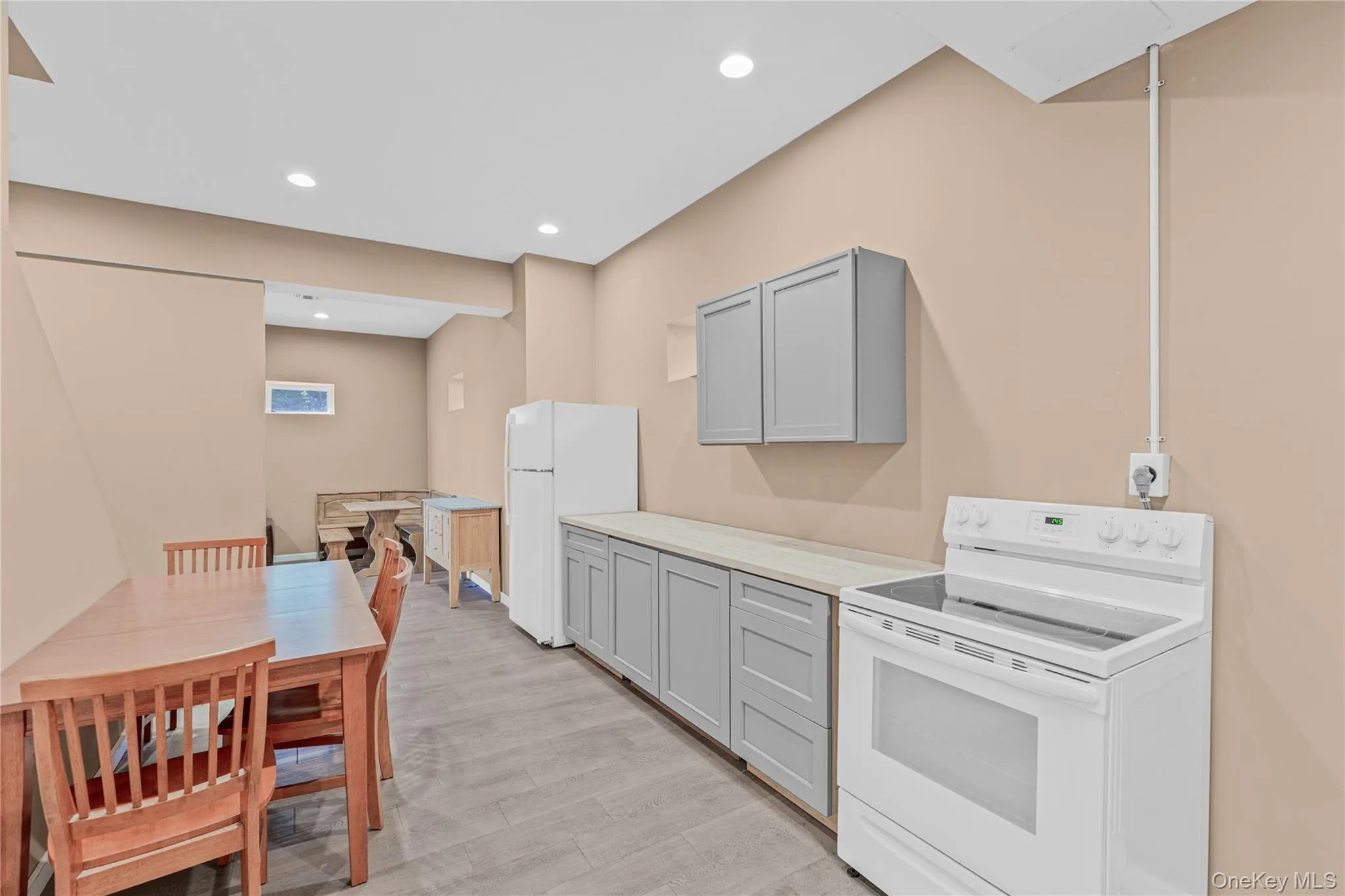 Kitchenette featuring white appliances, gray cabinetry, recessed lighting, light wood-style flooring, and light countertops Kitchenette featuring white appliances, gray cabinetry, recessed lighting, light wood-style flooring, and light countertops