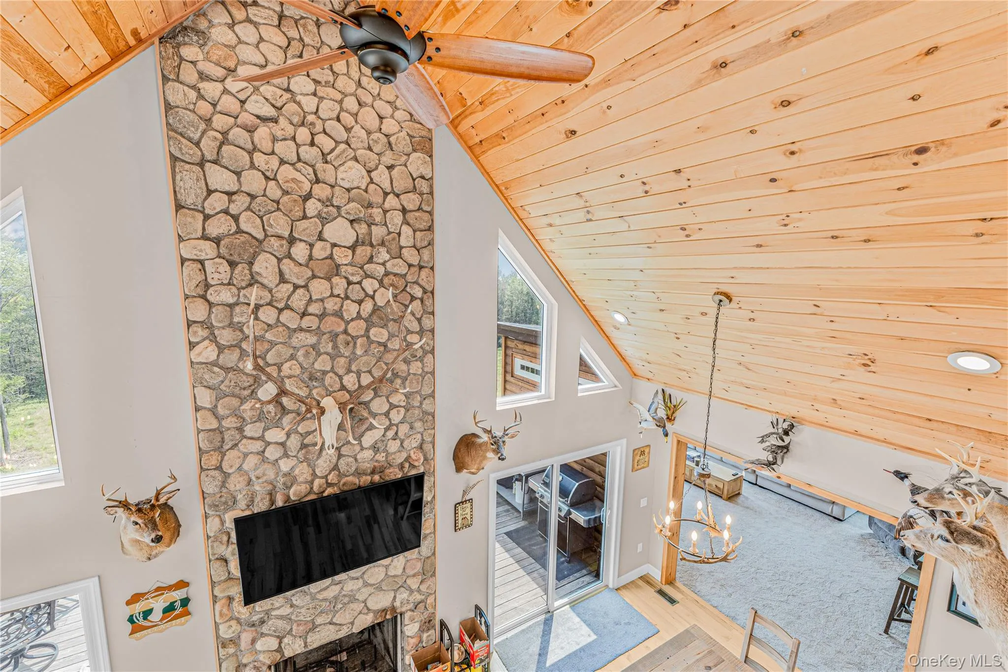Living room featuring high vaulted ceiling, wooden ceiling, a fireplace, a ceiling fan, and wood finished floors Living room featuring high vaulted ceiling, wooden ceiling, a fireplace, a ceiling fan, and wood finished floors