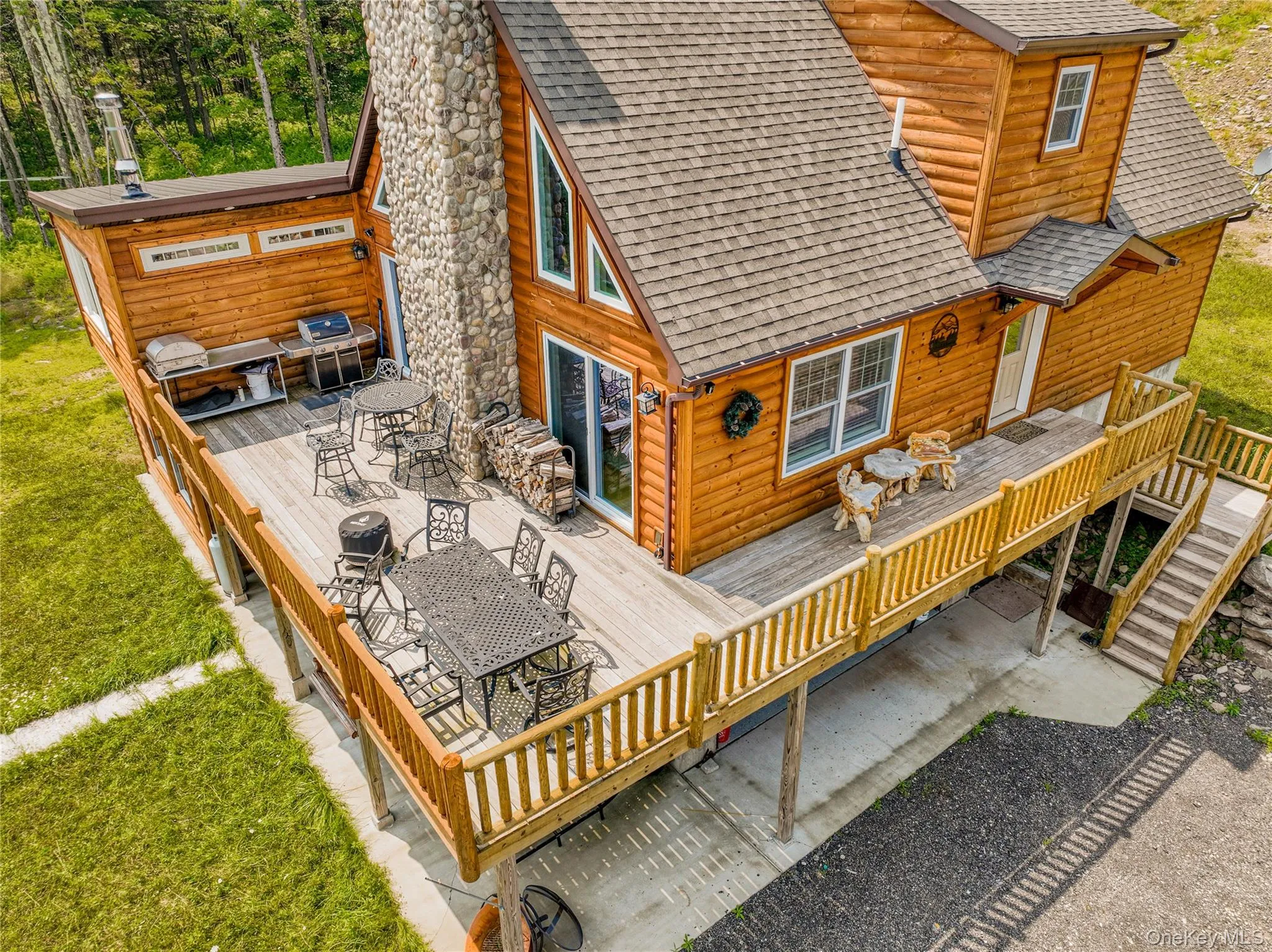 Back of house featuring faux log siding, a wooden deck, a shingled roof, and outdoor dining space Back of house featuring faux log siding, a wooden deck, a shingled roof, and outdoor dining space