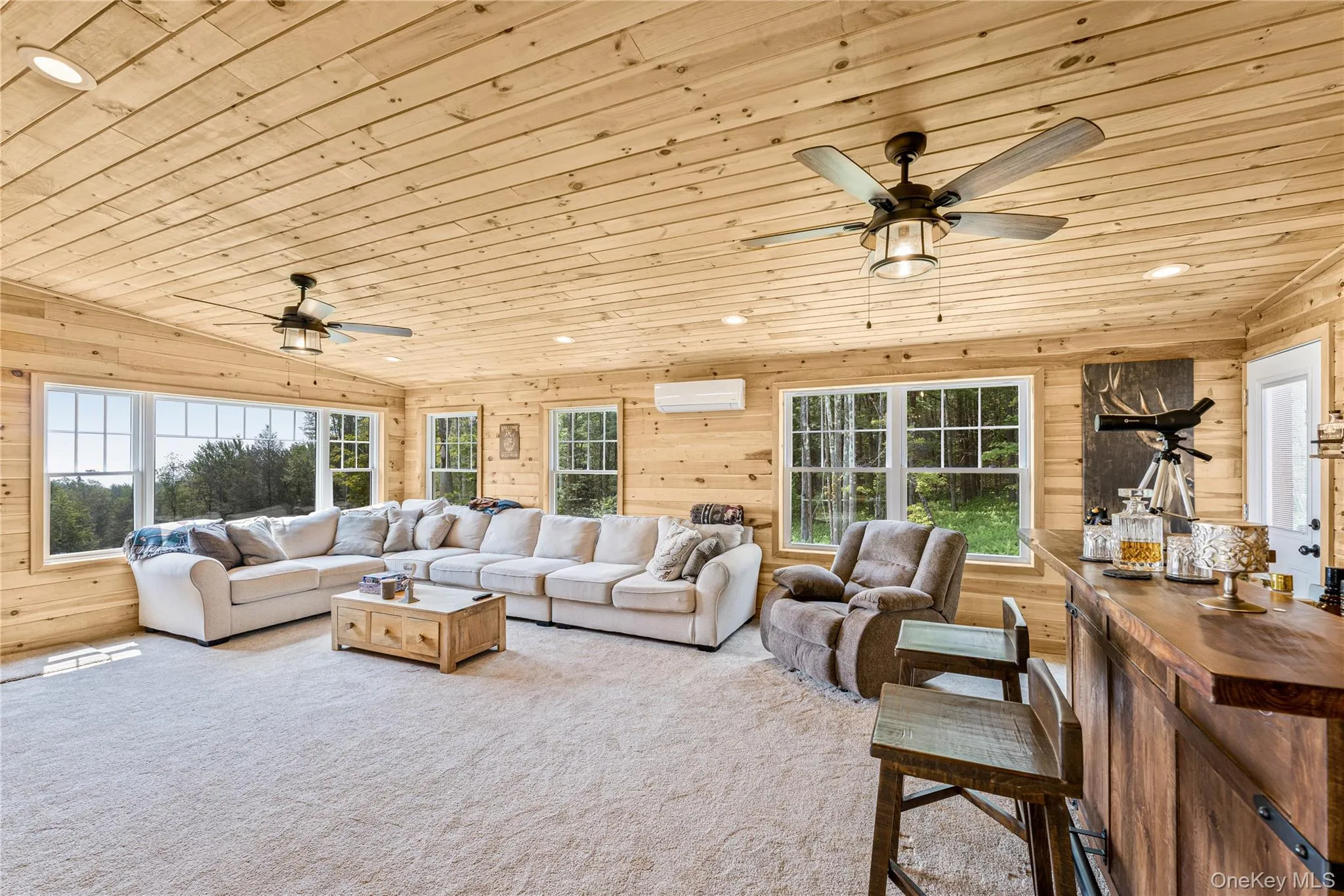 Carpeted living room with wooden ceiling, wood walls, recessed lighting, a ceiling fan, and a wall unit AC Carpeted living room with wooden ceiling, wood walls, recessed lighting, a ceiling fan, and a wall unit AC