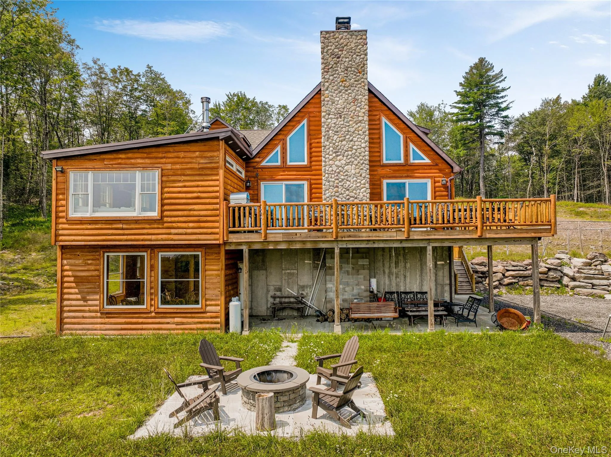 Back of property featuring a lawn, a fire pit, log veneer siding, and a wooden deck Back of property featuring a lawn, a fire pit, log veneer siding, and a wooden deck