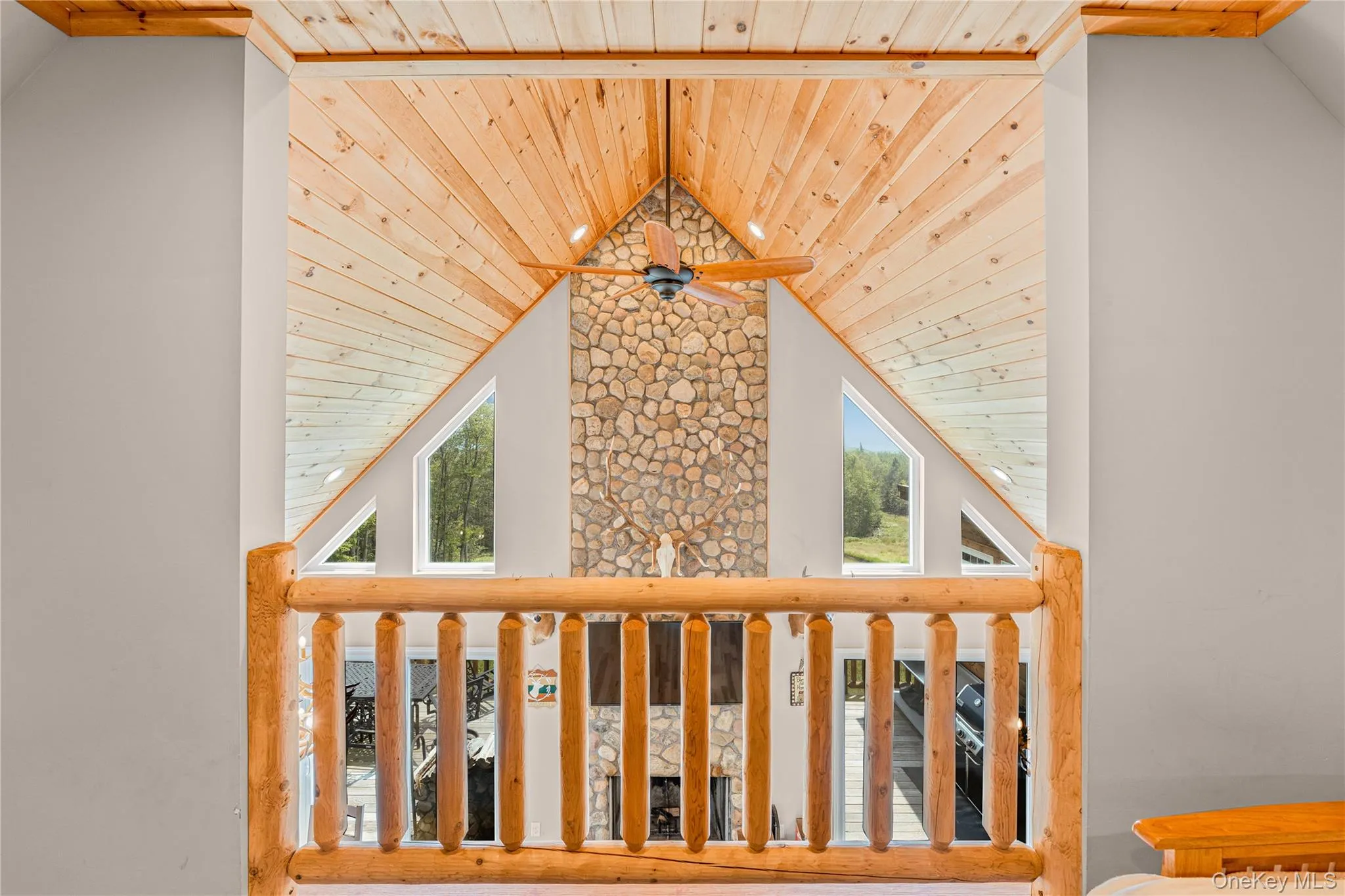 Balcony with a wooden ceiling with exposed beams, high vaulted ceiling, and ceiling fan Balcony with a wooden ceiling with exposed beams, high vaulted ceiling, and ceiling fan