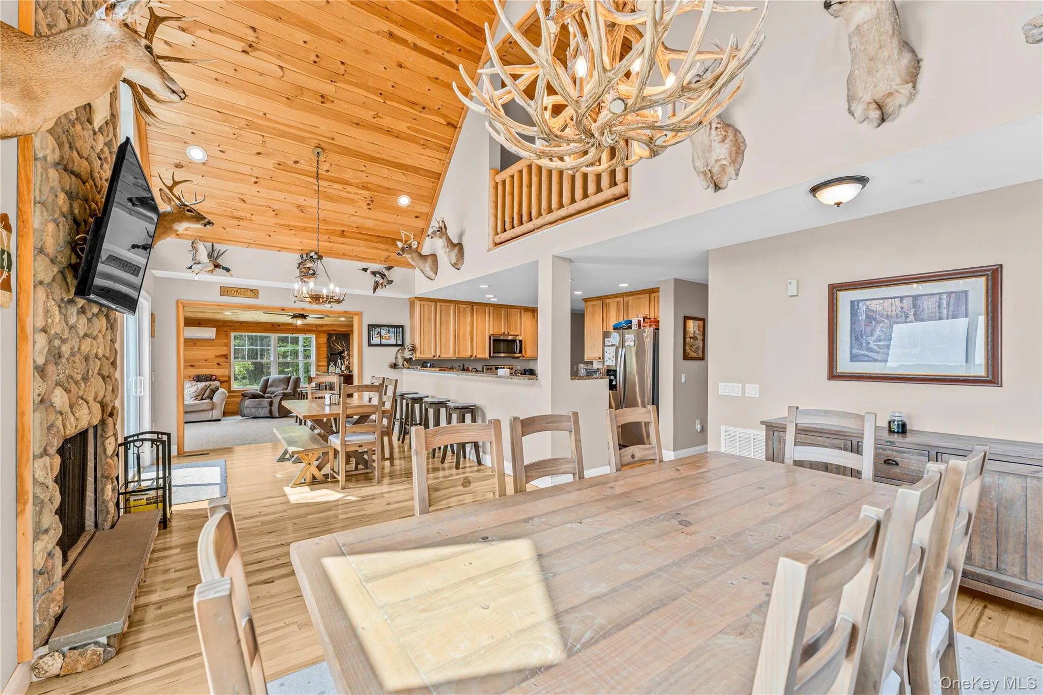 Dining room featuring high vaulted ceiling, a fireplace, a chandelier, light wood finished floors, and recessed lighting Dining room featuring high vaulted ceiling, a fireplace, a chandelier, light wood finished floors, and recessed lighting