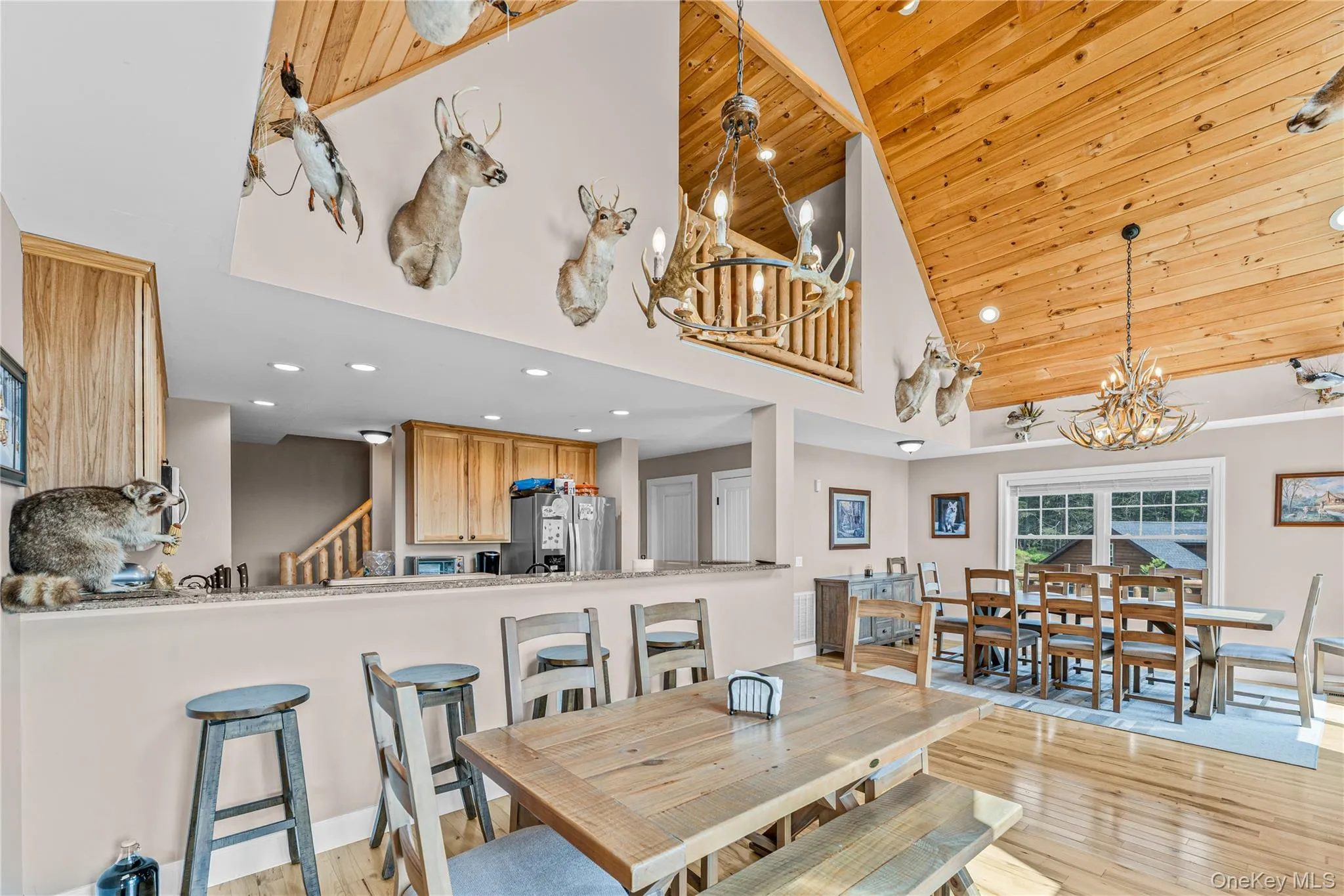 Dining space featuring high vaulted ceiling, light wood finished floors, recessed lighting, stairs, and a chandelier Dining space featuring high vaulted ceiling, light wood finished floors, recessed lighting, stairs, and a chandelier