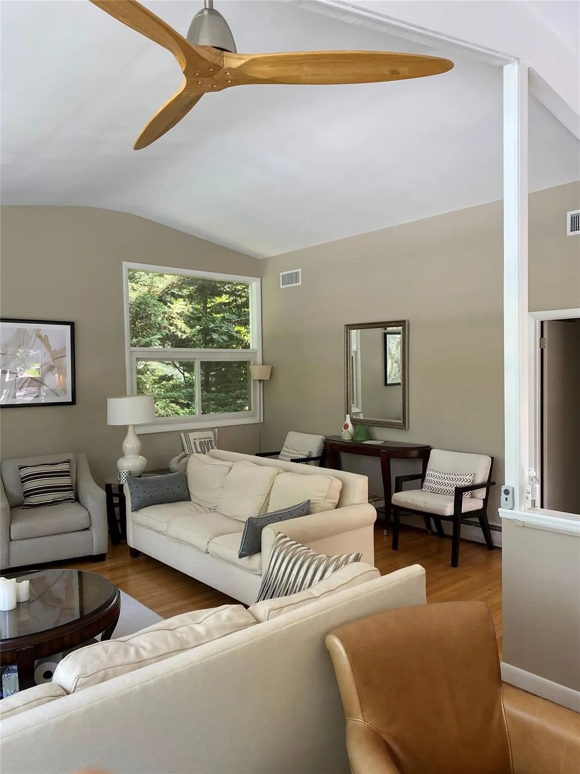Living room with ceiling fan, vaulted ceiling, and wood-type flooring Living room with ceiling fan, vaulted ceiling, and wood-type flooring