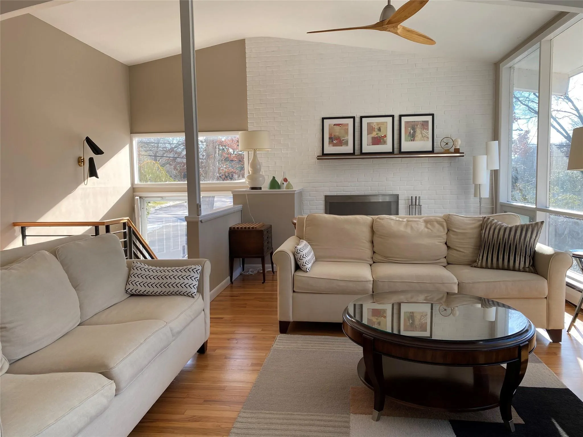 Living room with wood-type flooring, a healthy amount of sunlight, ceiling fan, and a fireplace Living room with wood-type flooring, a healthy amount of sunlight, ceiling fan, and a fireplace