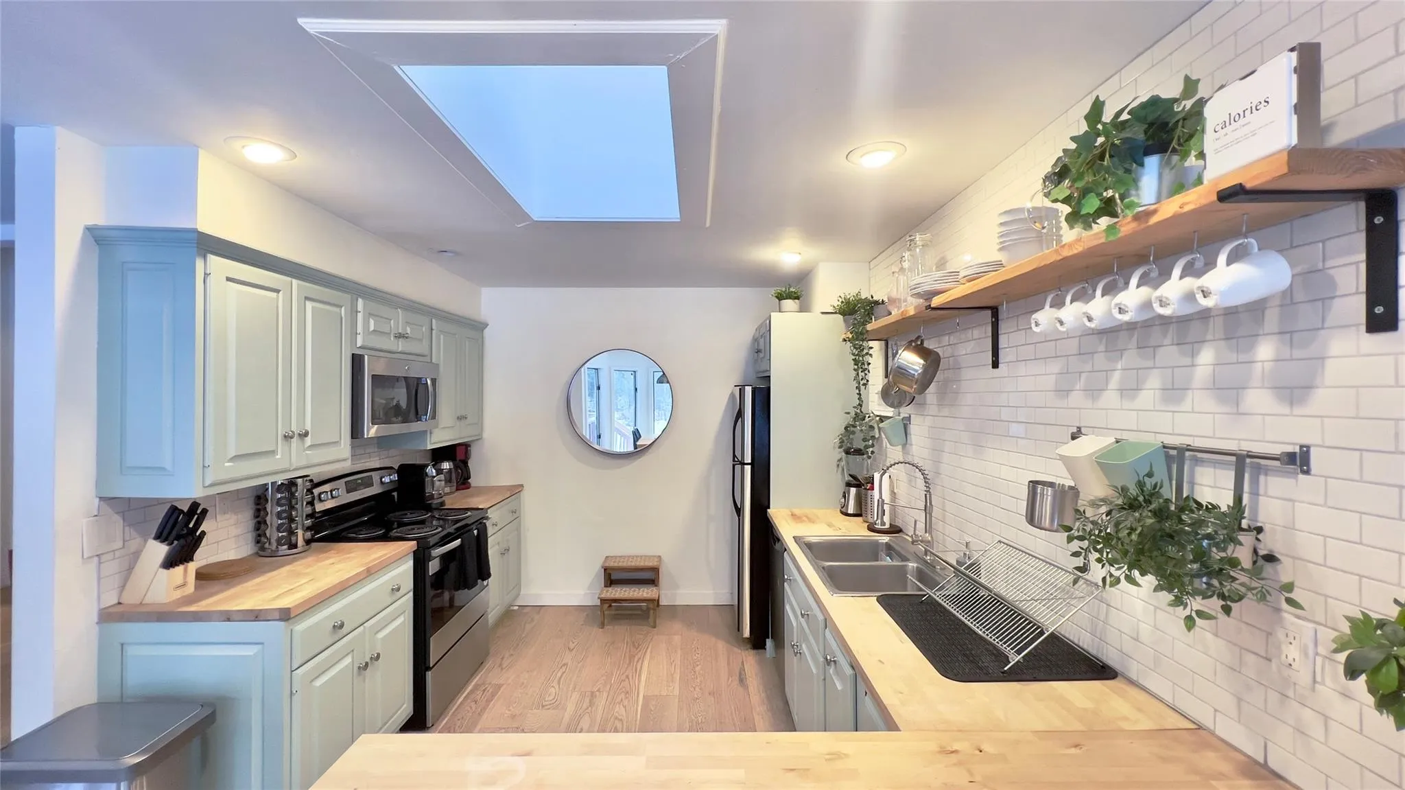 Kitchen with butcher block counters, sink, backsplash, light hardwood / wood-style floors, and stainless steel appliances Kitchen with butcher block counters, sink, backsplash, light hardwood / wood-style floors, and stainless steel appliances