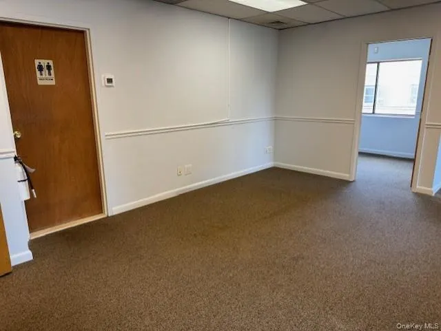 Spare room featuring carpet floors and a drop ceiling Spare room featuring carpet floors and a drop ceiling