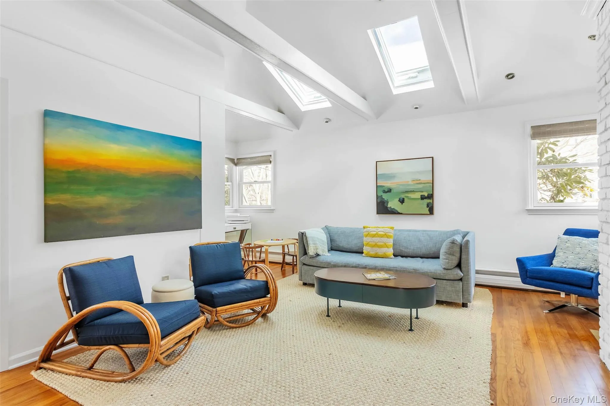 Living room with lofted ceiling with skylight, hardwood / wood-style floors, and a wealth of natural light Living room with lofted ceiling with skylight, hardwood / wood-style floors, and a wealth of natural light