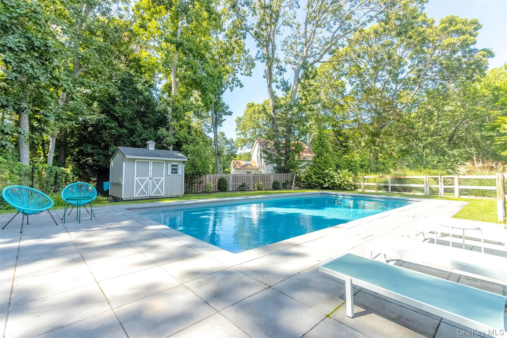 View of pool featuring a patio, view of wooded area, and a storage shed View of pool featuring a patio, view of wooded area, and a storage shed