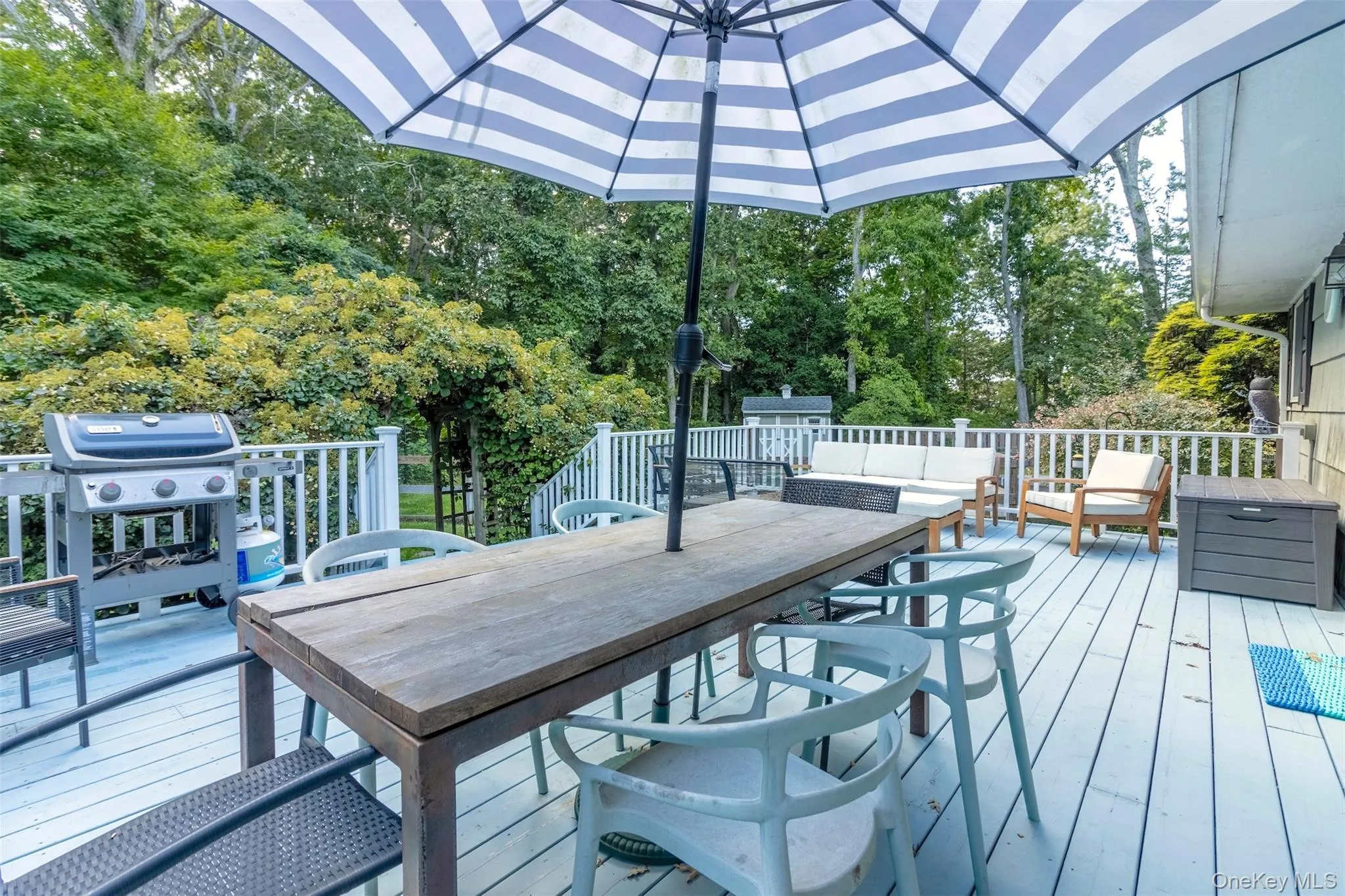 Wooden deck with outdoor dining space, view of scattered trees, and grilling area Wooden deck with outdoor dining space, view of scattered trees, and grilling area