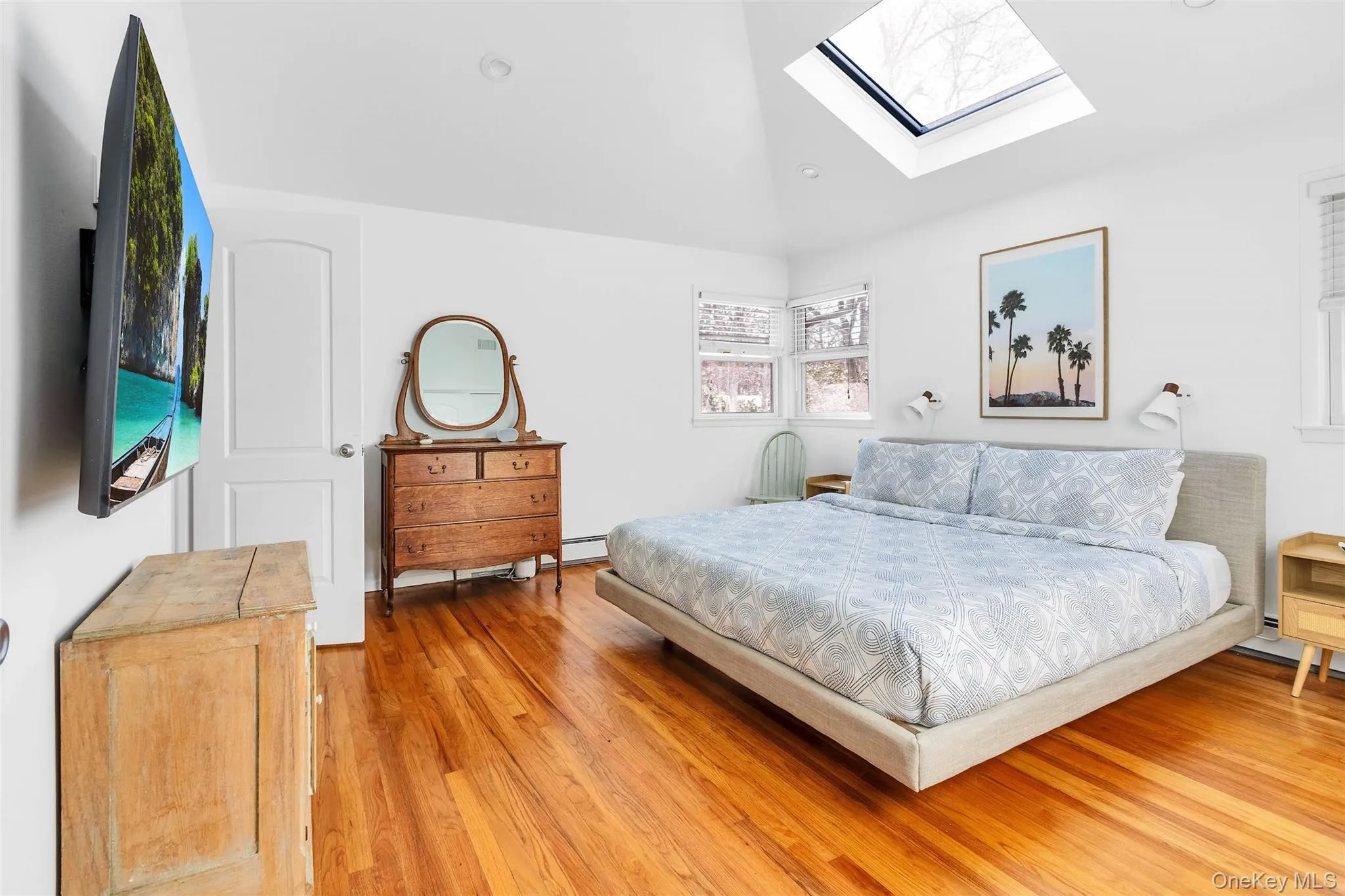 Bedroom featuring vaulted ceiling, a baseboard heating unit, and light wood-type flooring Bedroom featuring vaulted ceiling, a baseboard heating unit, and light wood-type flooring