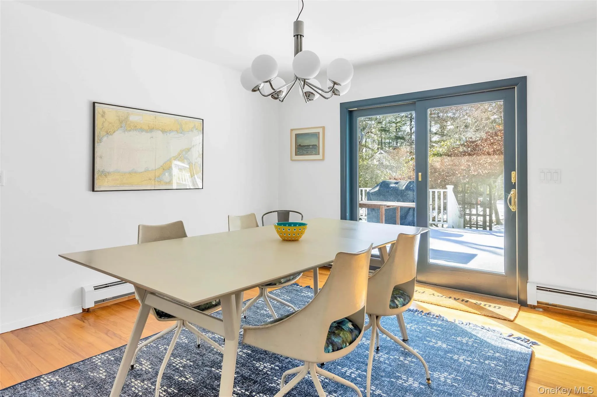 Dining room featuring a chandelier, hardwood / wood-style floors, and baseboard heating Dining room featuring a chandelier, hardwood / wood-style floors, and baseboard heating