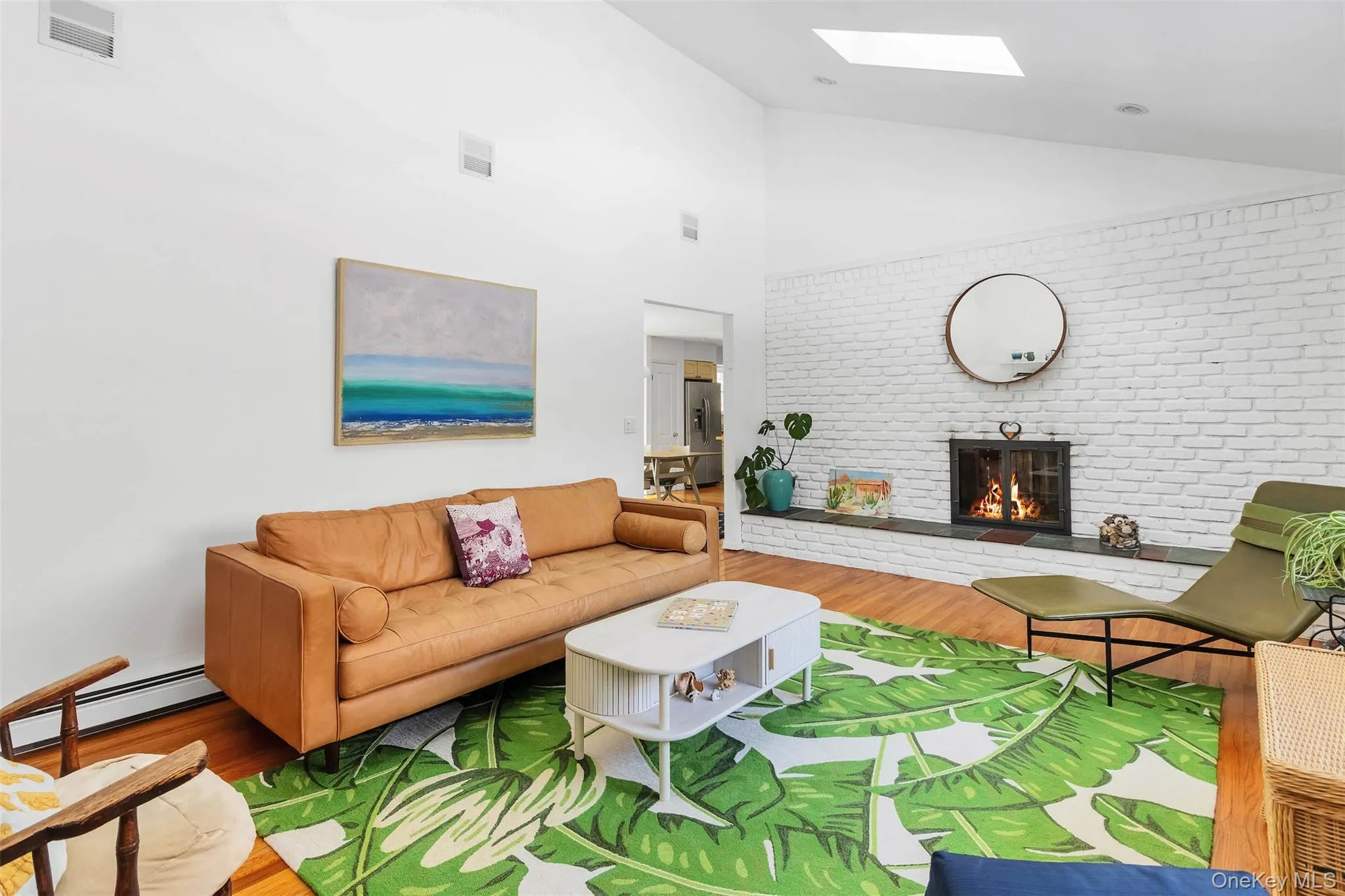 Living room with a baseboard heating unit, a skylight, a fireplace, wood-type flooring, and brick wall Living room with a baseboard heating unit, a skylight, a fireplace, wood-type flooring, and brick wall