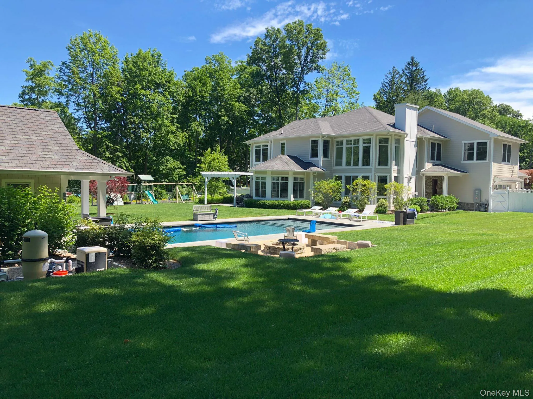 Rendering of back of property featuring a patio area, an outdoor pool, a yard, and a playground and pool house. Rendering of back of property featuring a patio area, an outdoor pool, a yard, and a playground and pool house.