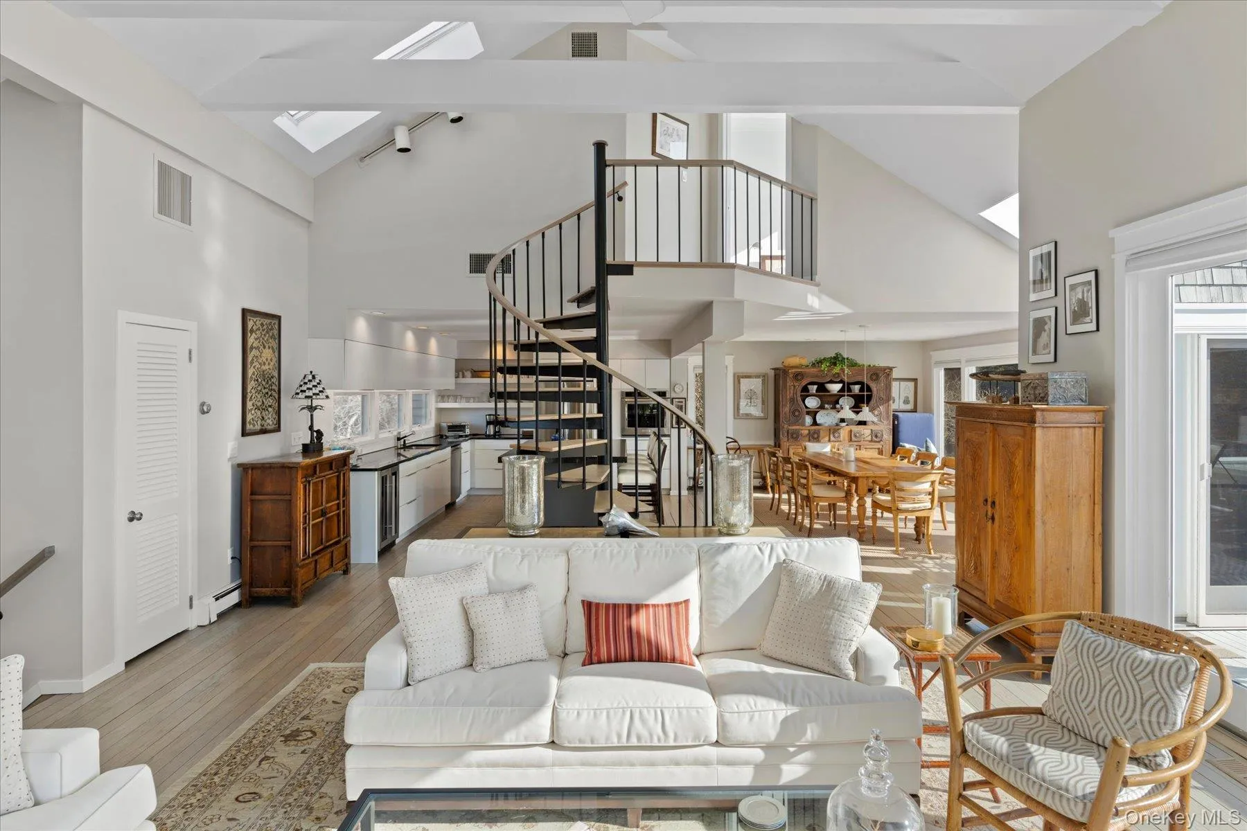 Living room with beamed ceiling, light hardwood / wood-style floors, a skylight, a baseboard radiator, and high vaulted ceiling Living room with beamed ceiling, light hardwood / wood-style floors, a skylight, a baseboard radiator, and high vaulted ceiling