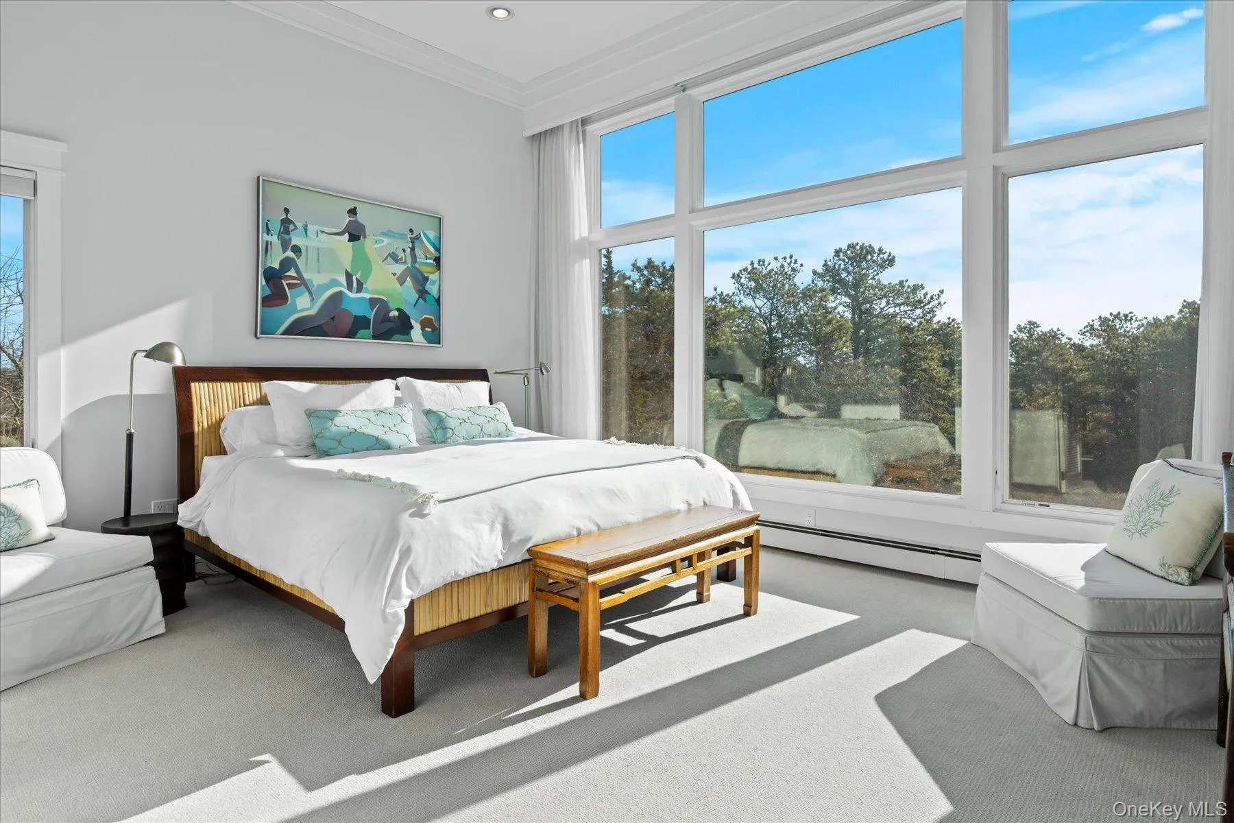 Carpeted primary bedroom featuring crown molding and baseboard heating and Window walls with views Carpeted primary bedroom featuring crown molding and baseboard heating and Window walls with views