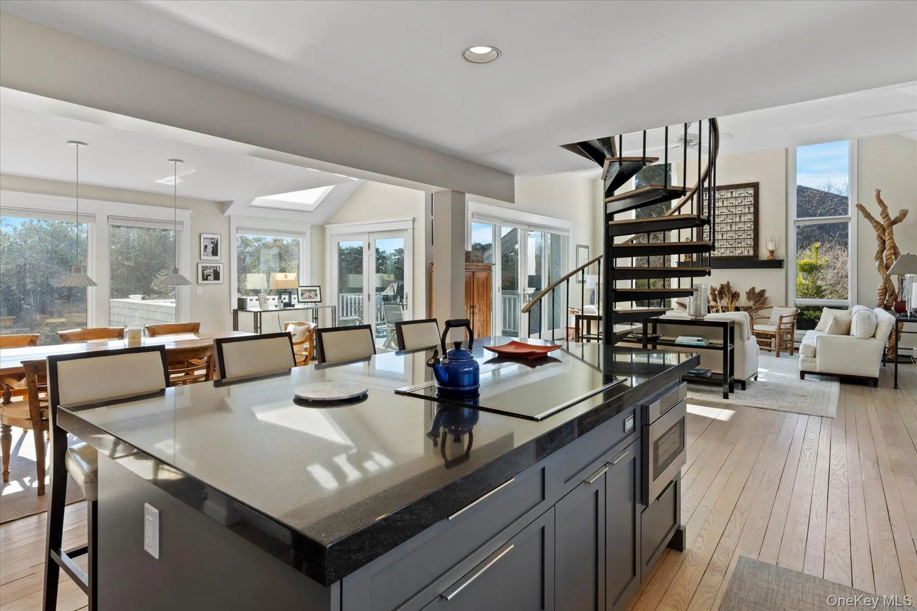 Kitchen featuring a kitchen island, decorative light fixtures, gray cabinets, stainless steel microwave, and light hardwood / wood-style flooring Kitchen featuring a kitchen island, decorative light fixtures, gray cabinets, stainless steel microwave, and light hardwood / wood-style flooring