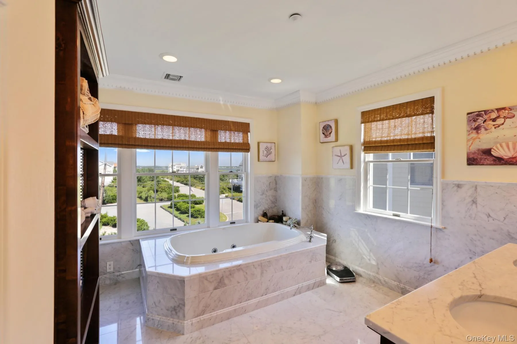 Bathroom with a relaxing tiled tub, vanity, crown molding, and tile walls Bathroom with a relaxing tiled tub, vanity, crown molding, and tile walls