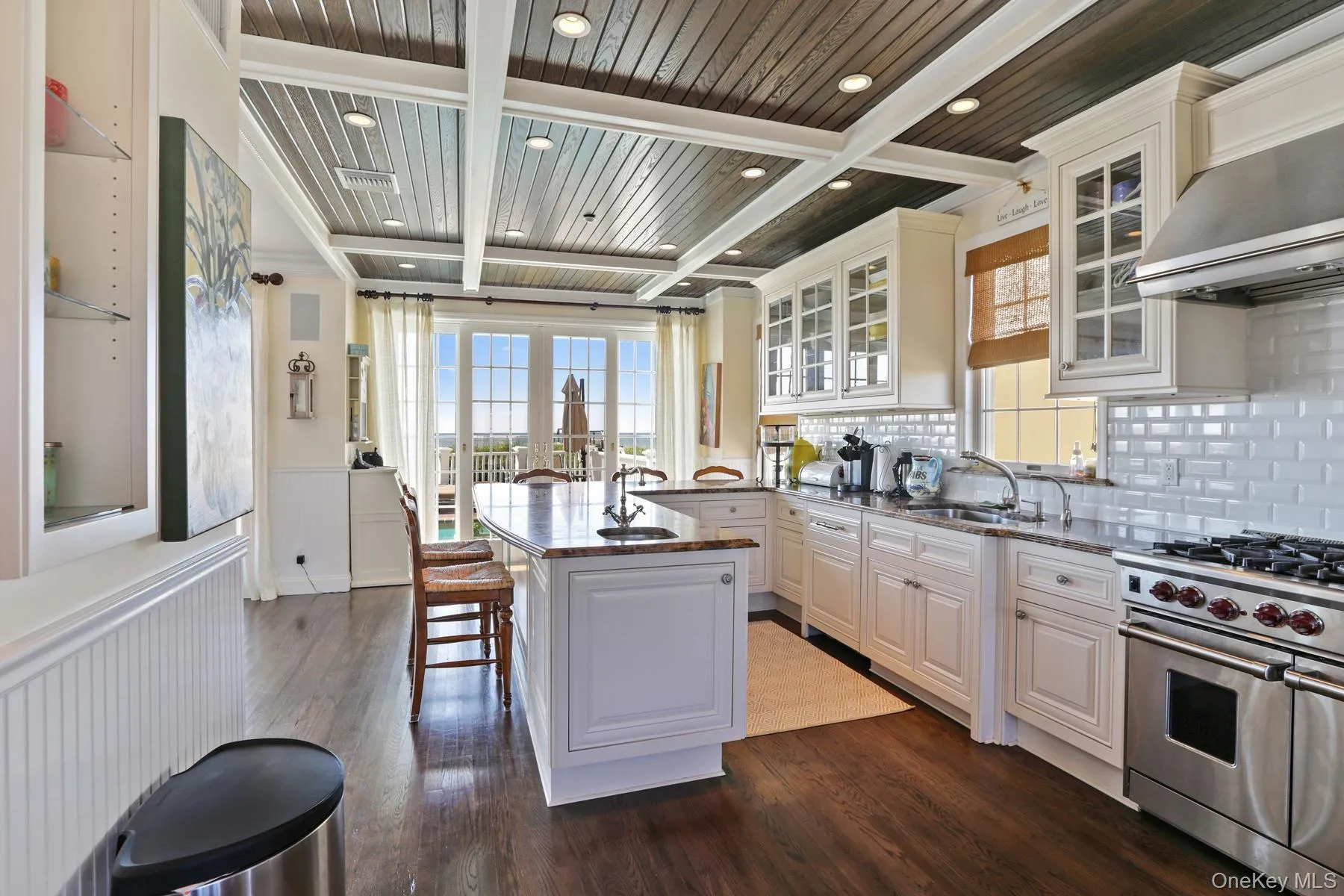 Kitchen featuring exhaust hood, sink, white cabinetry, a center island, and double oven range Kitchen featuring exhaust hood, sink, white cabinetry, a center island, and double oven range