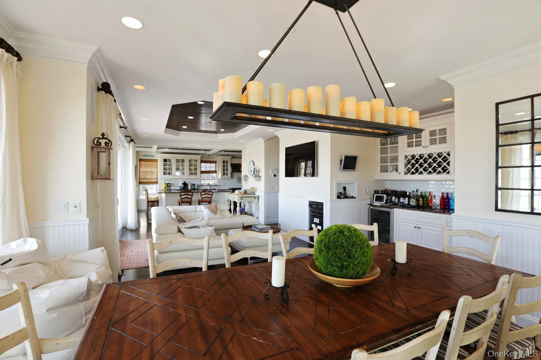 Dining room featuring wine cooler, a tray ceiling, ornamental molding, and indoor bar Dining room featuring wine cooler, a tray ceiling, ornamental molding, and indoor bar