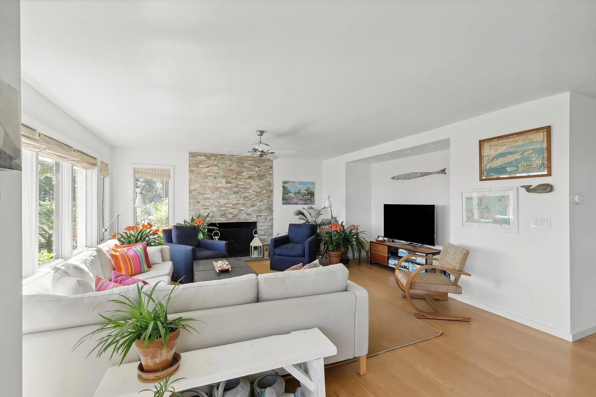 Living room with hardwood / wood-style floors, ceiling fan, and a stone fireplace Living room with hardwood / wood-style floors, ceiling fan, and a stone fireplace