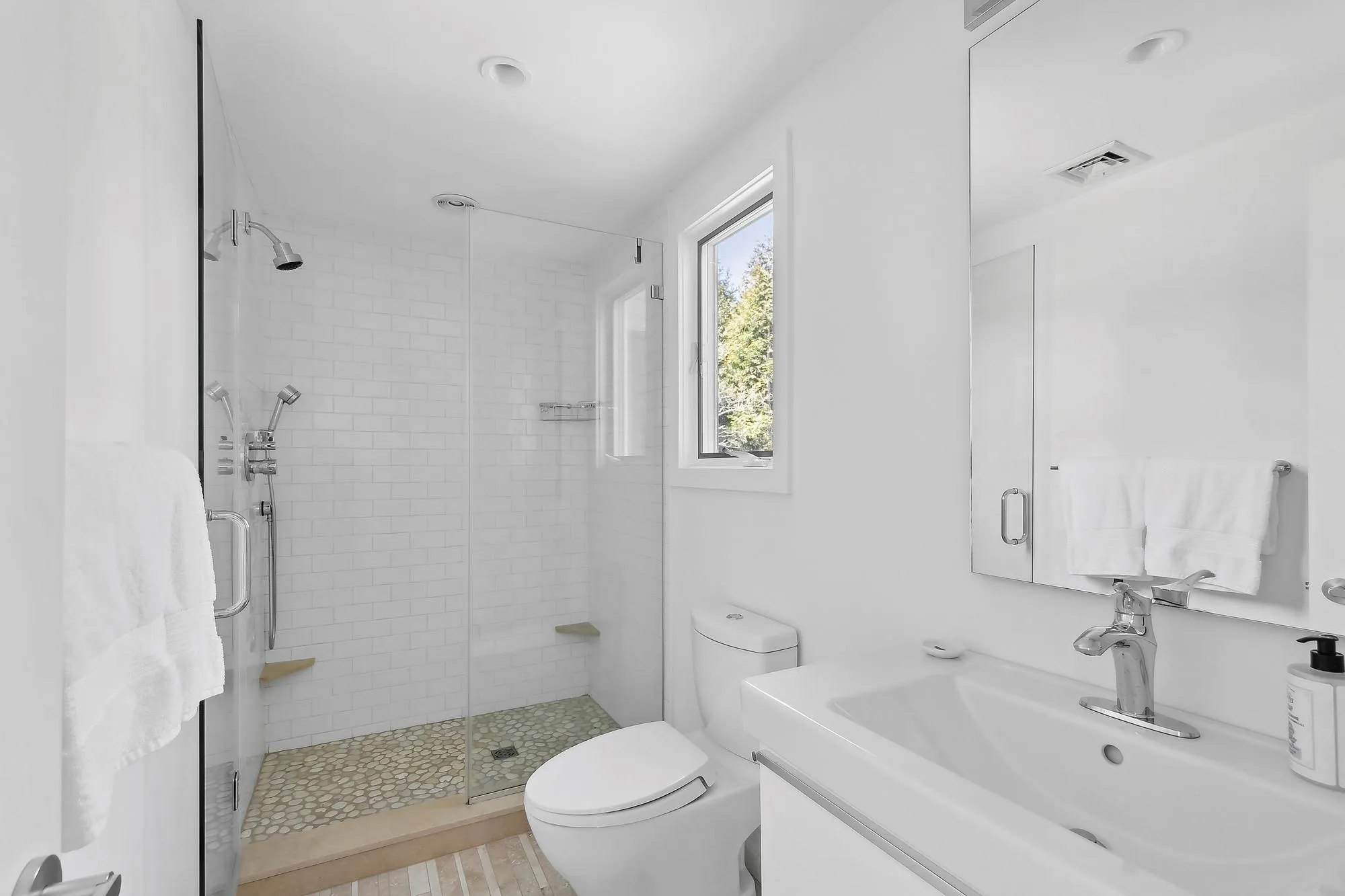 Bathroom featuring toilet, vanity, and a shower with shower door Bathroom featuring toilet, vanity, and a shower with shower door