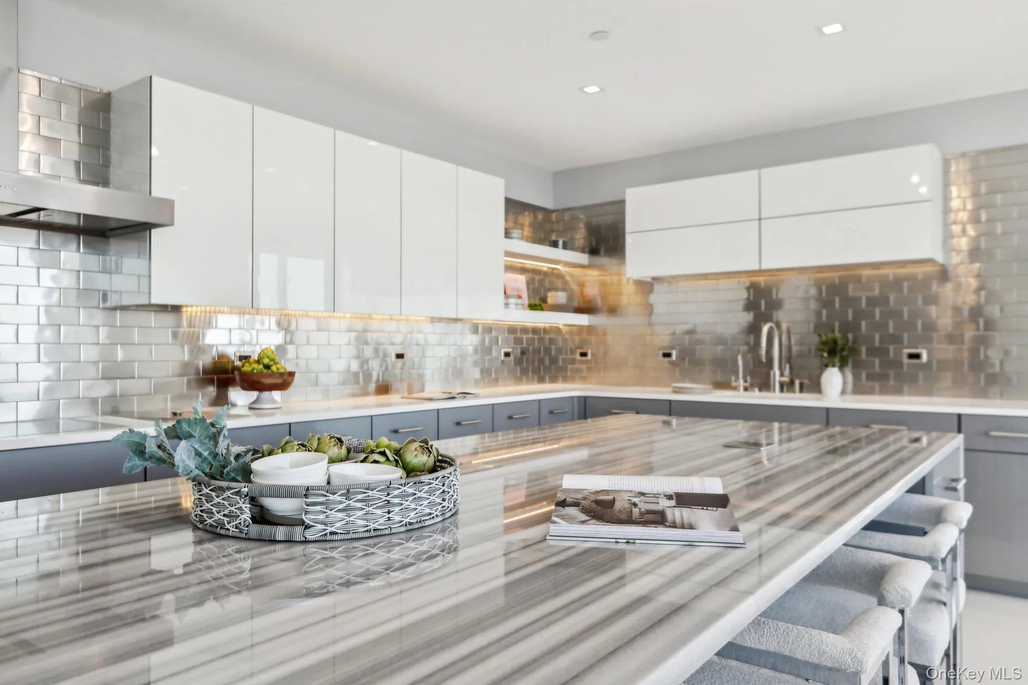 Kitchen featuring light countertops, wall chimney range hood, decorative backsplash, and modern cabinets Kitchen featuring light countertops, wall chimney range hood, decorative backsplash, and modern cabinets