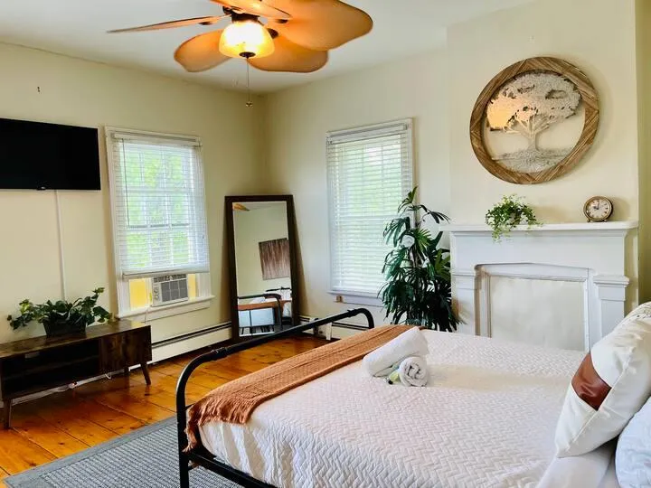 Bedroom 1 with ceiling fan, hardwood / wood-style flooring, multiple windows, and a fireplace Bedroom 1 with ceiling fan, hardwood / wood-style flooring, multiple windows, and a fireplace