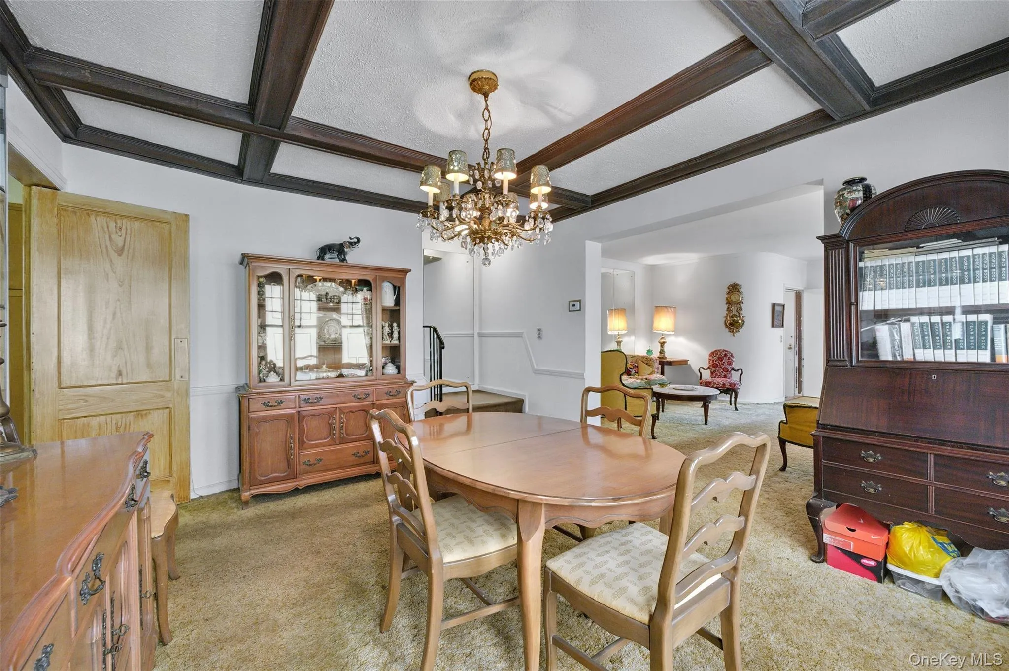 Dining area featuring coffered ceiling, a notable chandelier, beamed ceiling, a textured ceiling, and light colored carpet Dining area featuring coffered ceiling, a notable chandelier, beamed ceiling, a textured ceiling, and light colored carpet