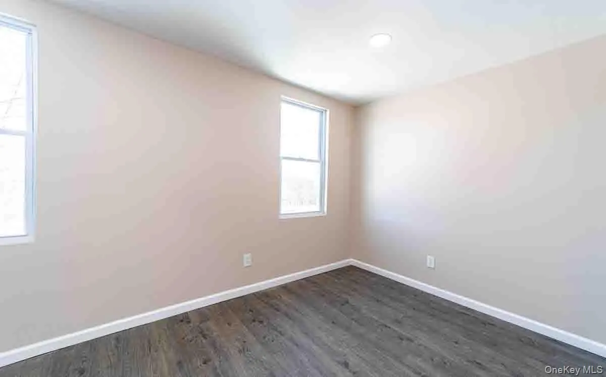 Spare room with dark wood-style floors and baseboards Spare room with dark wood-style floors and baseboards