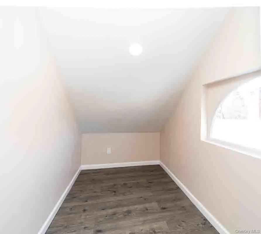 Bonus room with dark wood-type flooring, lofted ceiling, and baseboards Bonus room with dark wood-type flooring, lofted ceiling, and baseboards