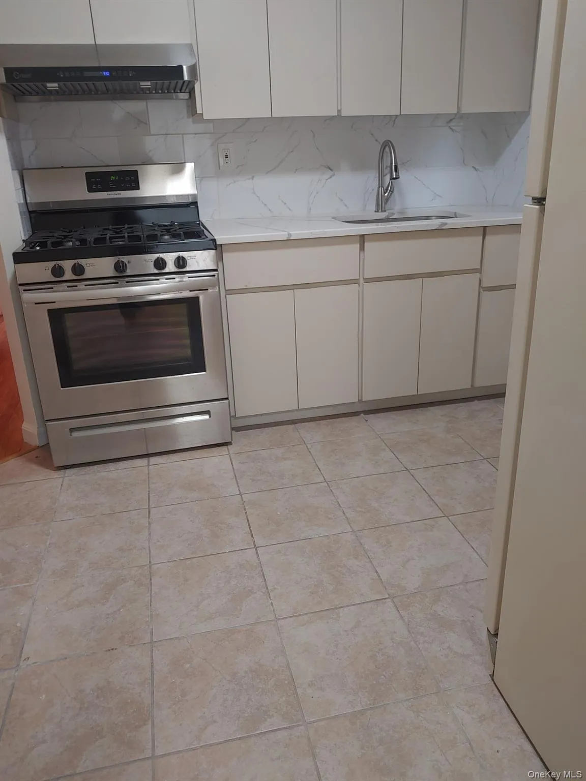 Kitchen featuring gas stove, ventilation hood, decorative backsplash, and freestanding refrigerator Kitchen featuring gas stove, ventilation hood, decorative backsplash, and freestanding refrigerator