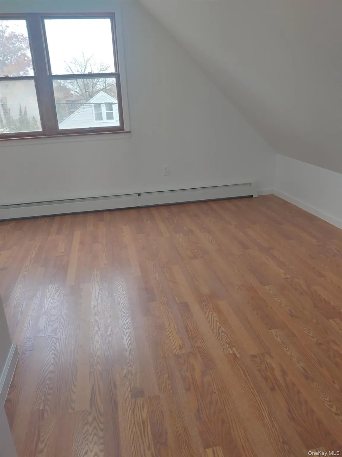 Additional living space with baseboard heating, light wood-style floors, and lofted ceiling Additional living space with baseboard heating, light wood-style floors, and lofted ceiling