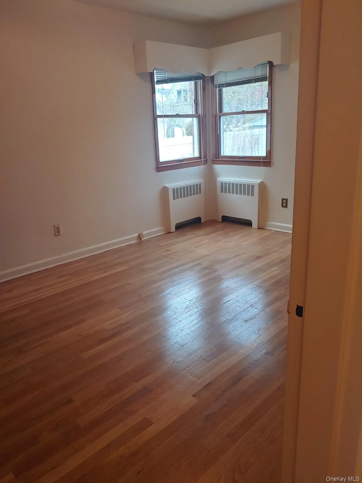 Empty room with light wood-style floors and radiator heating unit Empty room with light wood-style floors and radiator heating unit