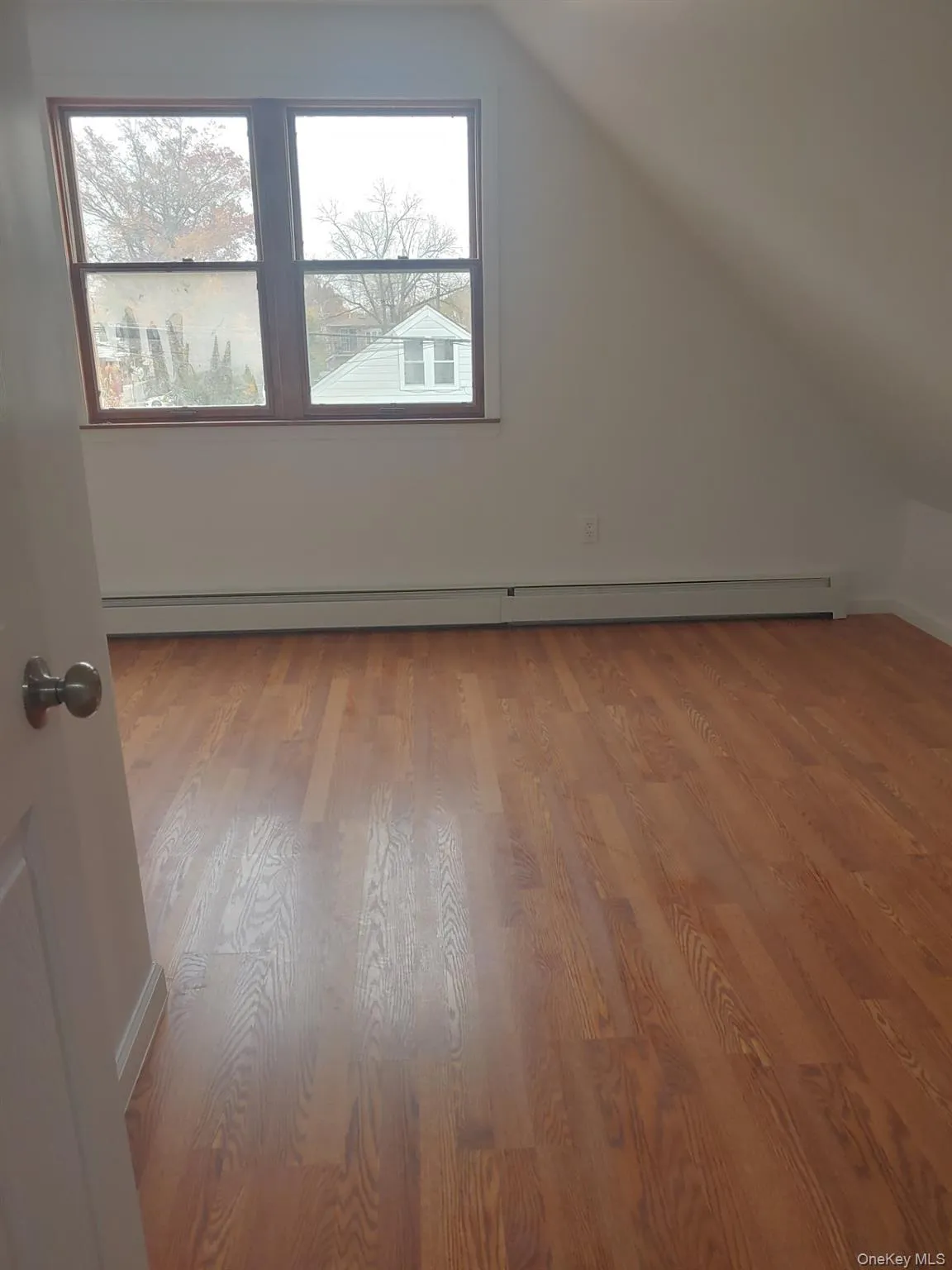 Additional living space featuring vaulted ceiling, light wood-style flooring, and baseboard heating Additional living space featuring vaulted ceiling, light wood-style flooring, and baseboard heating