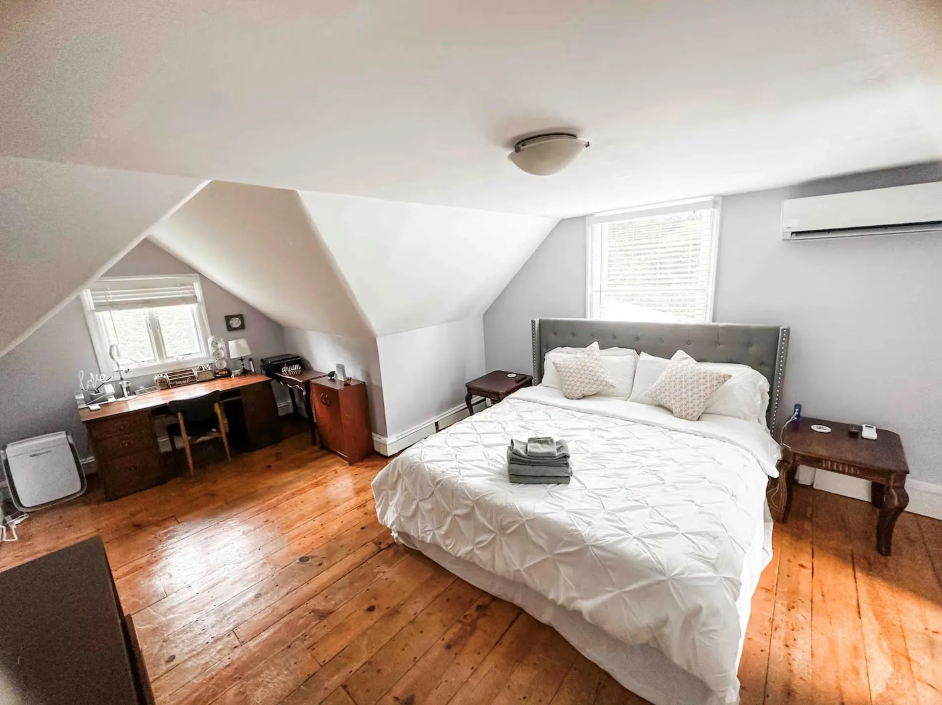 Bedroom with lofted ceiling, light wood finished floors, a wall mounted AC, and baseboards Bedroom with lofted ceiling, light wood finished floors, a wall mounted AC, and baseboards