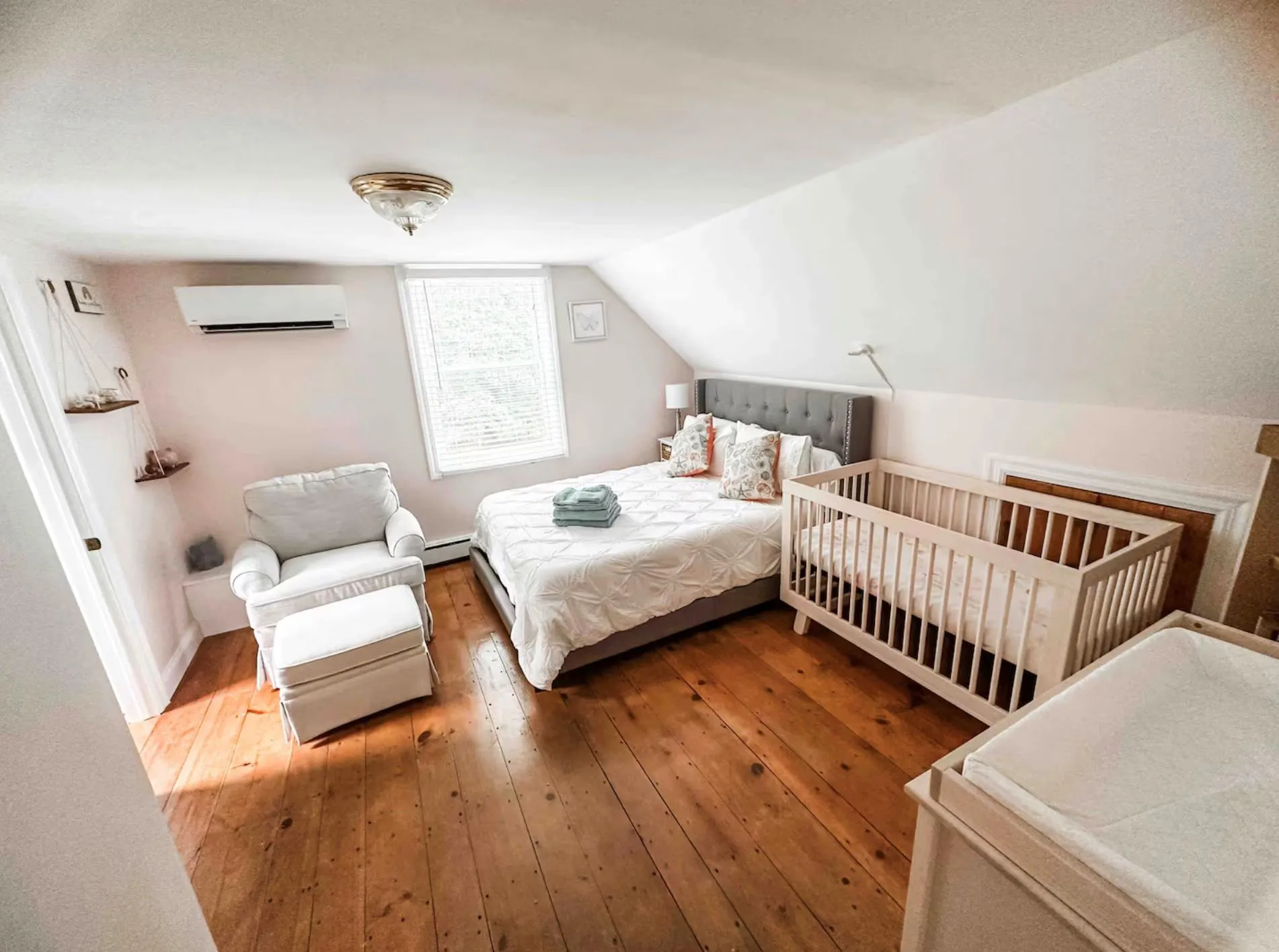 Bedroom featuring lofted ceiling, a wall mounted air conditioner, wood finished floors, and a baseboard radiator Bedroom featuring lofted ceiling, a wall mounted air conditioner, wood finished floors, and a baseboard radiator