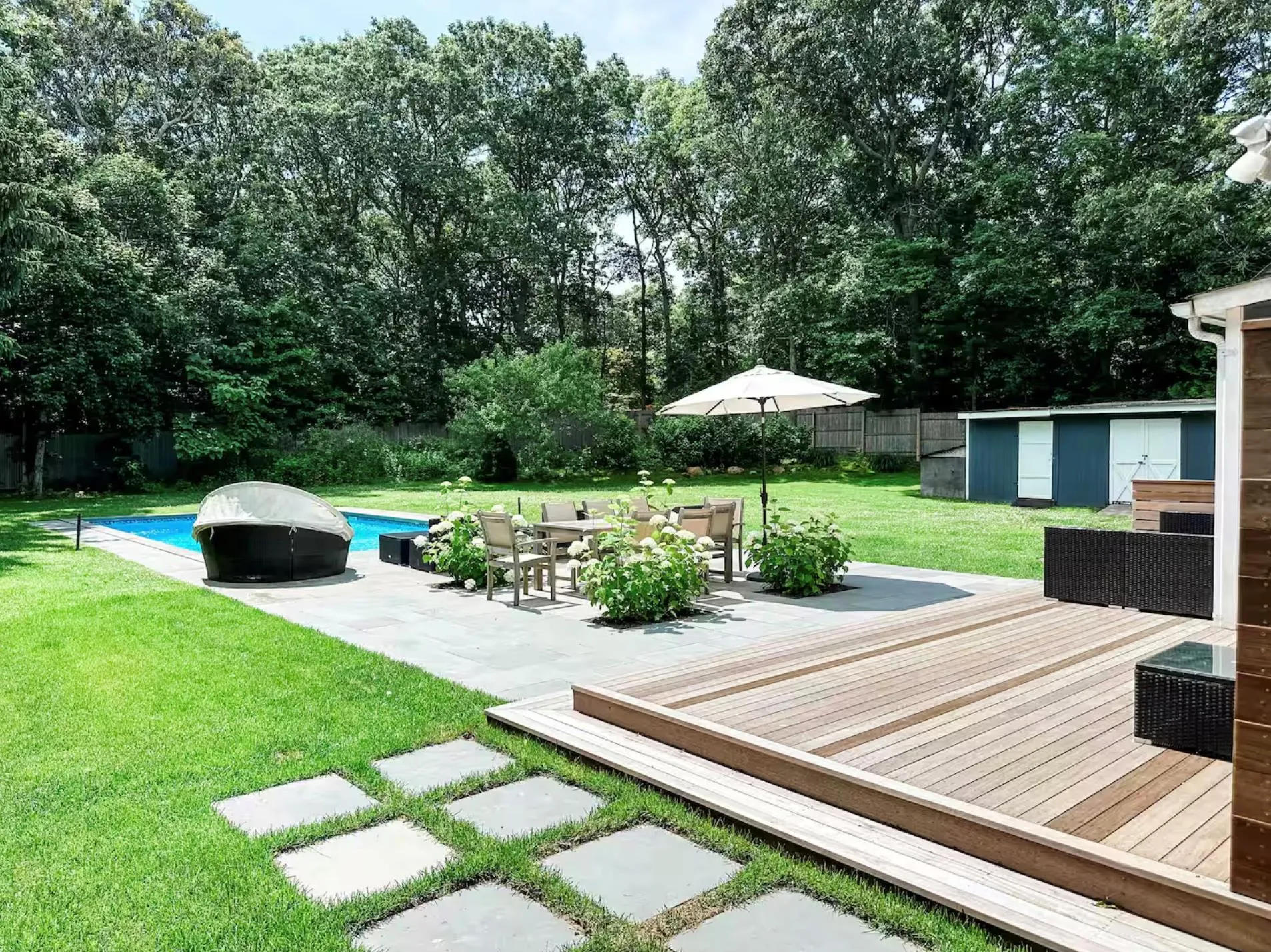 View of yard featuring an outbuilding, outdoor dining space, a deck, a fenced backyard, and an outdoor pool View of yard featuring an outbuilding, outdoor dining space, a deck, a fenced backyard, and an outdoor pool