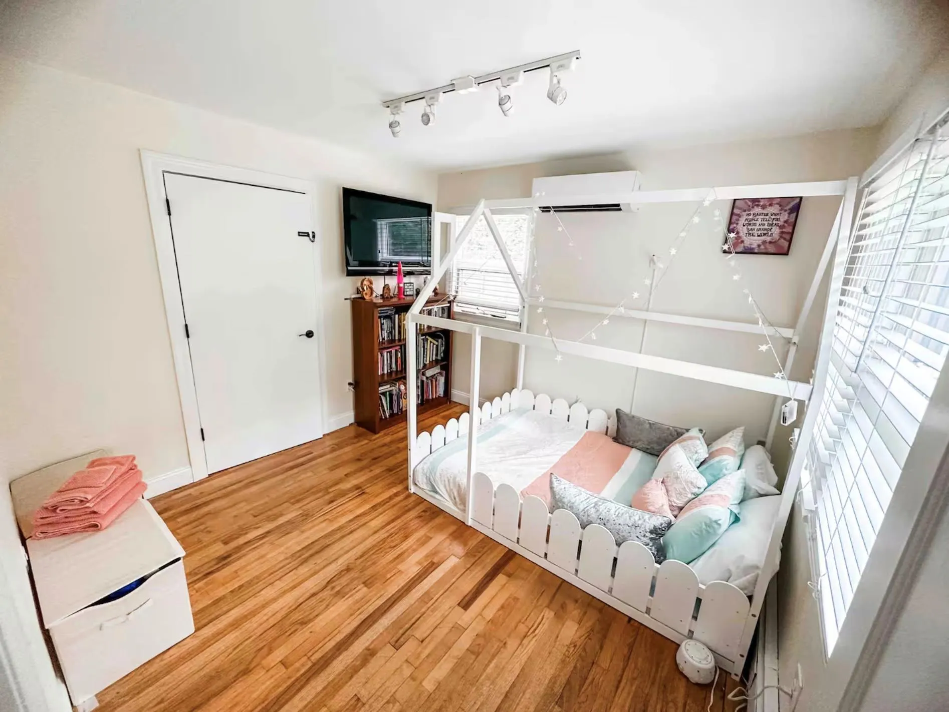 Bedroom with light wood-type flooring, rail lighting, and a wall mounted AC Bedroom with light wood-type flooring, rail lighting, and a wall mounted AC