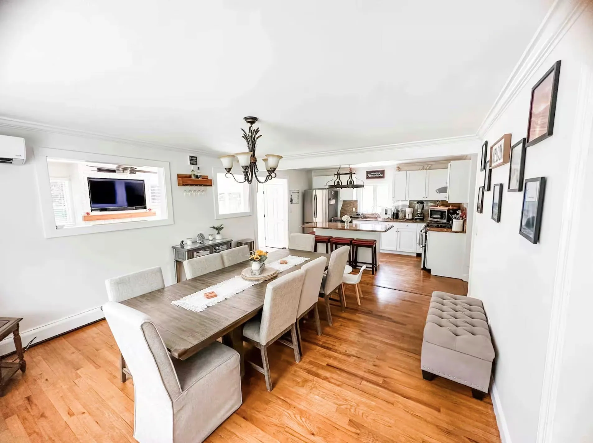 Dining area with baseboards, ornamental molding, an AC wall unit, light wood-style floors, and a notable chandelier Dining area with baseboards, ornamental molding, an AC wall unit, light wood-style floors, and a notable chandelier
