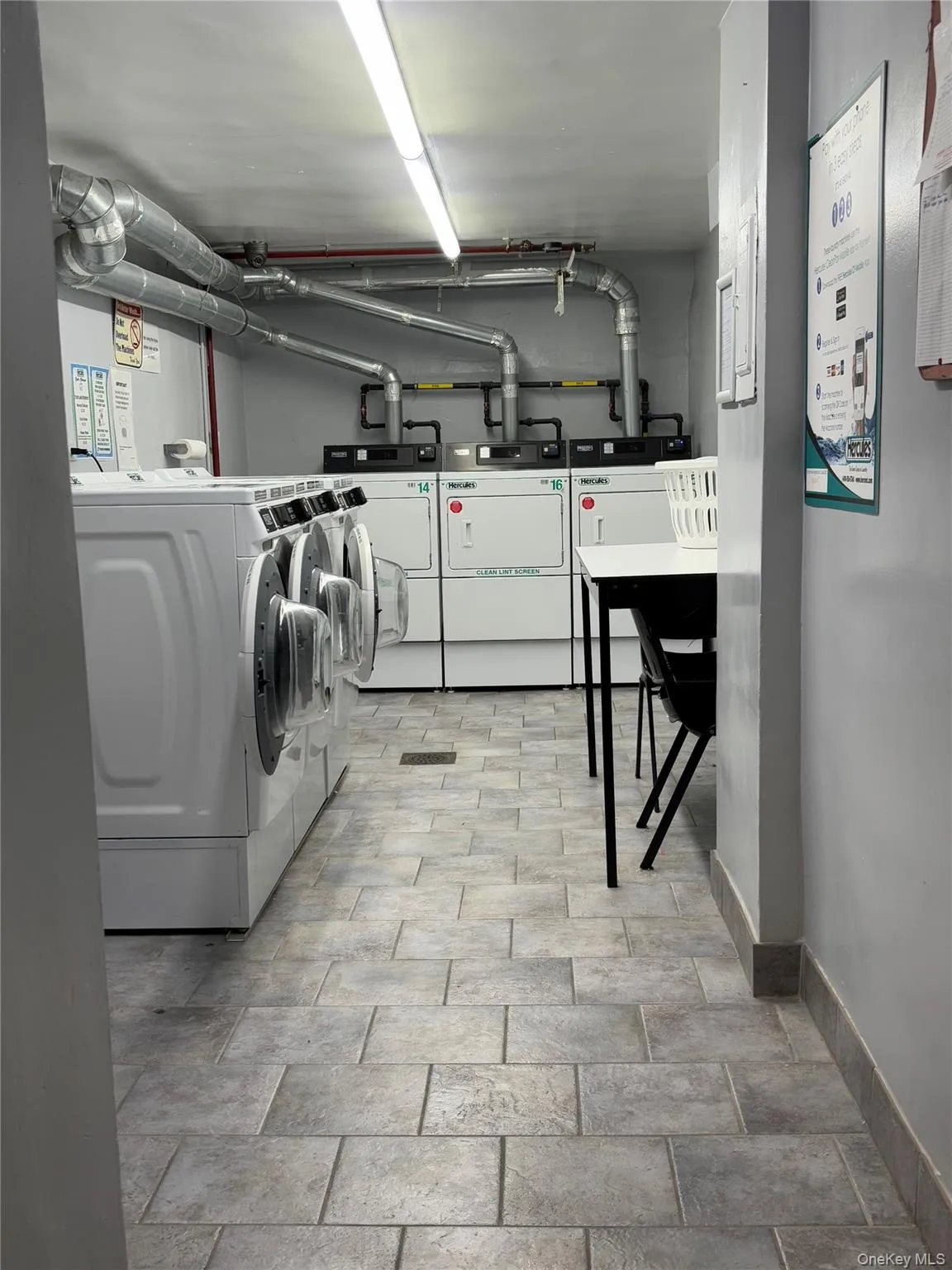 Community laundry room with stone finish floor, washing machine and dryer, and baseboards Community laundry room with stone finish floor, washing machine and dryer, and baseboards