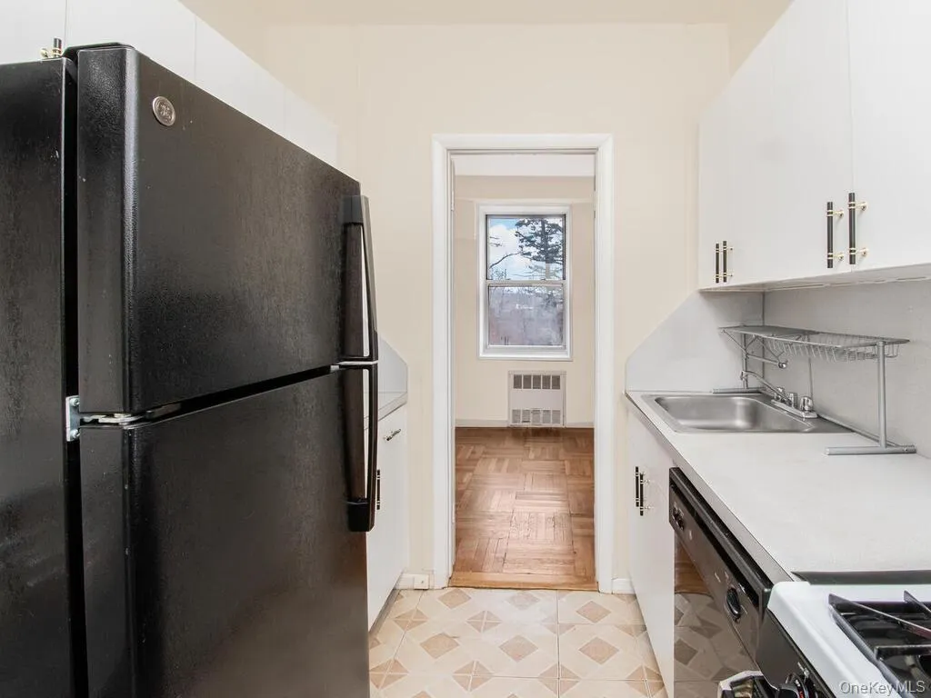 Kitchen featuring a sink, black appliances, light countertops, and white cabinets Kitchen featuring a sink, black appliances, light countertops, and white cabinets