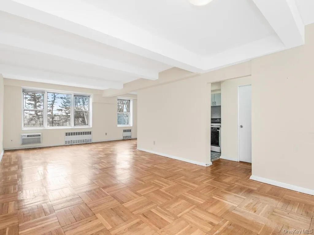 Unfurnished room featuring radiator heating unit, baseboards, and an AC wall unit Unfurnished room featuring radiator heating unit, baseboards, and an AC wall unit