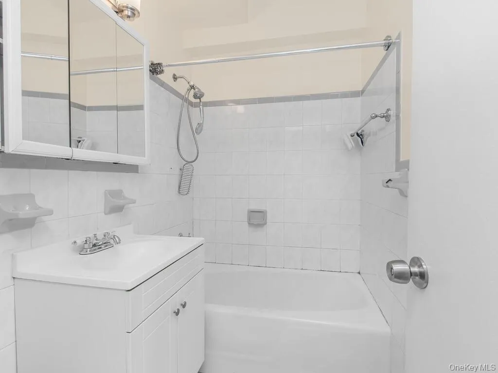 Bathroom featuring shower combination, tile walls, vanity, and decorative backsplash Bathroom featuring shower combination, tile walls, vanity, and decorative backsplash