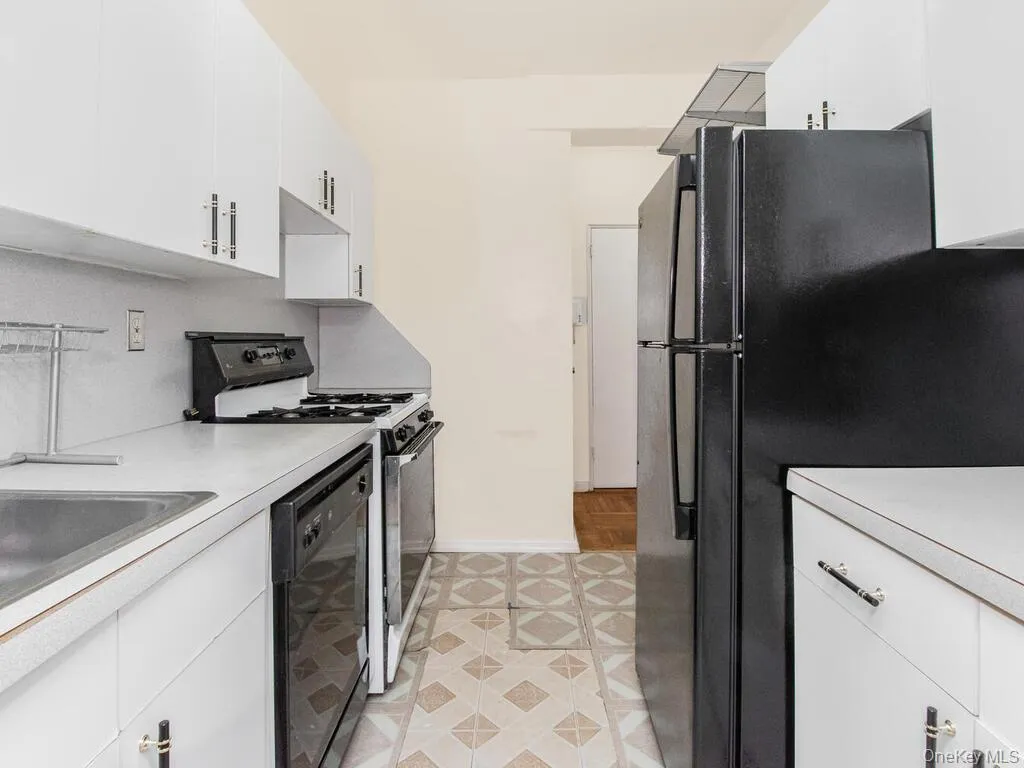 Kitchen with baseboards, light countertops, black appliances, and white cabinets Kitchen with baseboards, light countertops, black appliances, and white cabinets