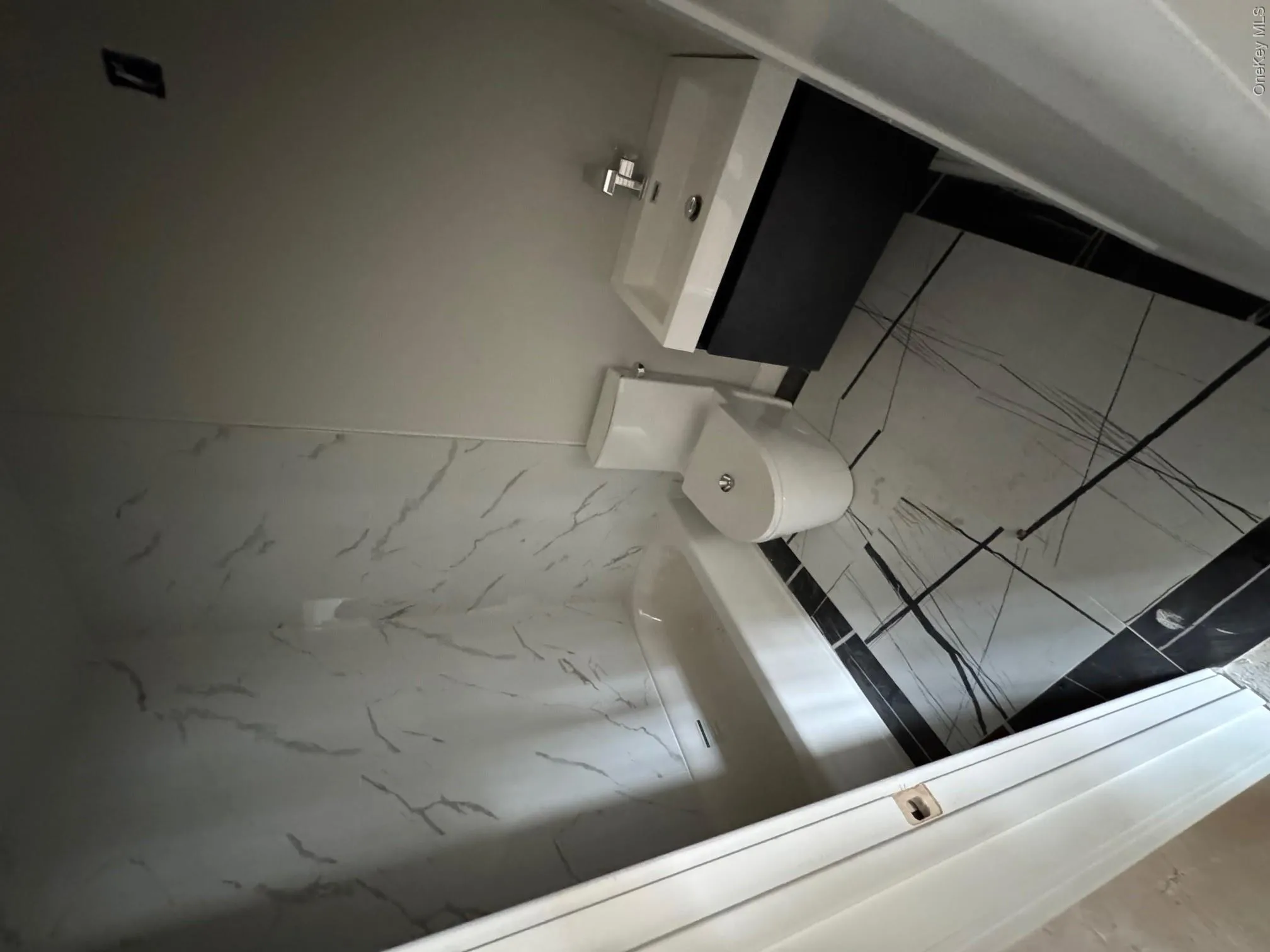 Full bath featuring a tub, marble finish floor, vanity, and toilet Full bath featuring a tub, marble finish floor, vanity, and toilet