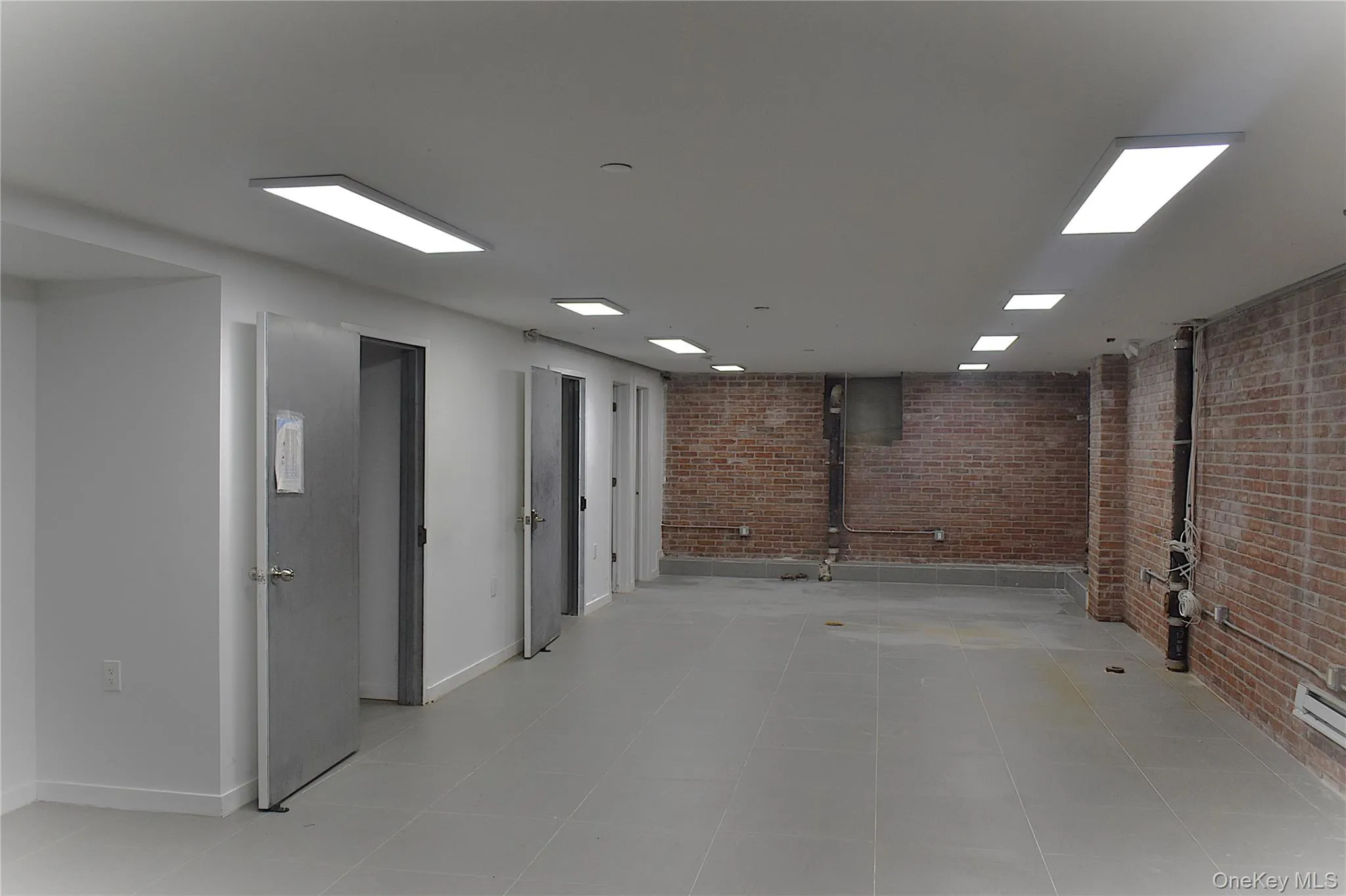 Finished basement featuring brick wall and baseboards Finished basement featuring brick wall and baseboards