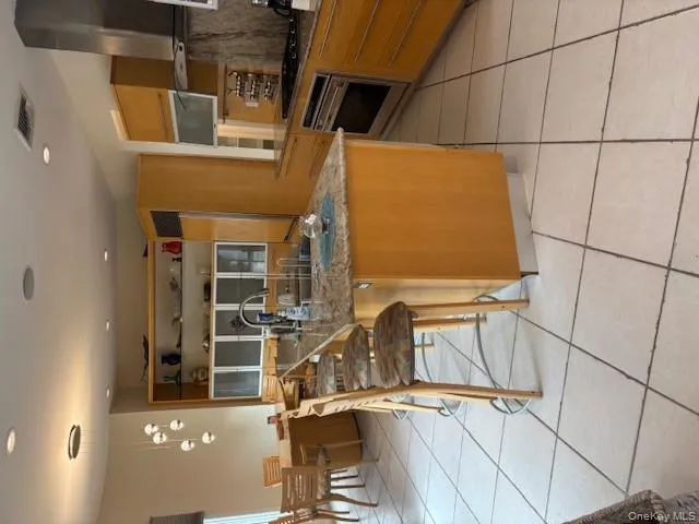 Kitchen with dark stone counters, light tile patterned flooring, exhaust hood, hanging light fixtures, and recessed lighting Kitchen with dark stone counters, light tile patterned flooring, exhaust hood, hanging light fixtures, and recessed lighting