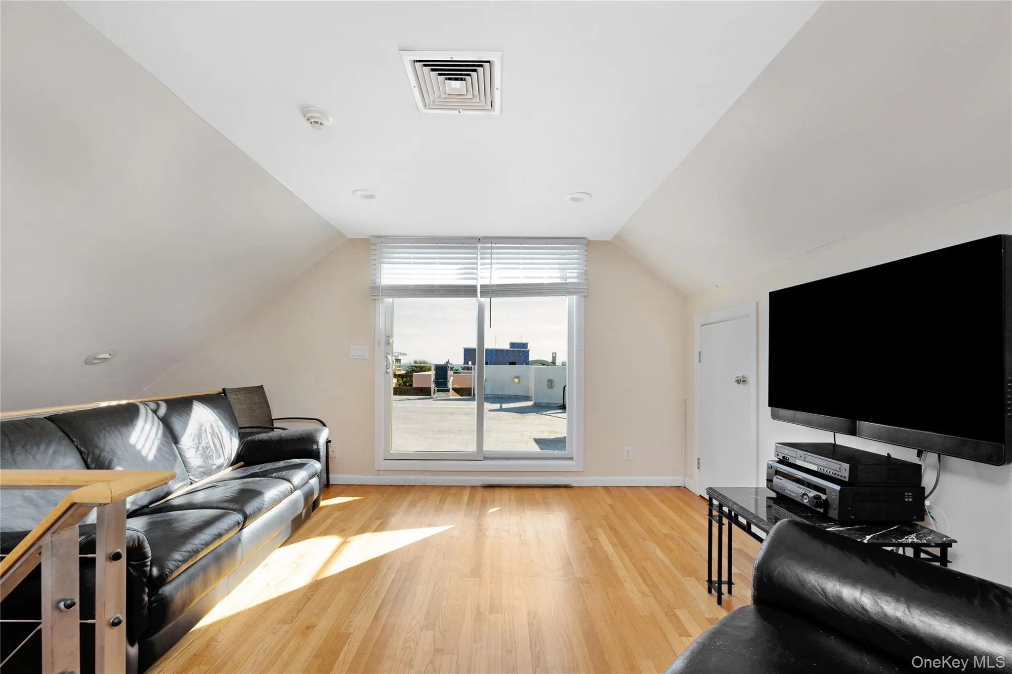 Living area featuring lofted ceiling, visible vents, baseboards, and wood finished floors Living area featuring lofted ceiling, visible vents, baseboards, and wood finished floors
